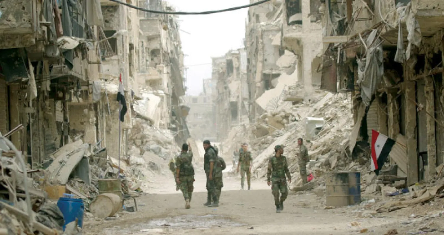 جنود سوريون وسط الدمار في مخيم اليرموك (إ.ب.أ)