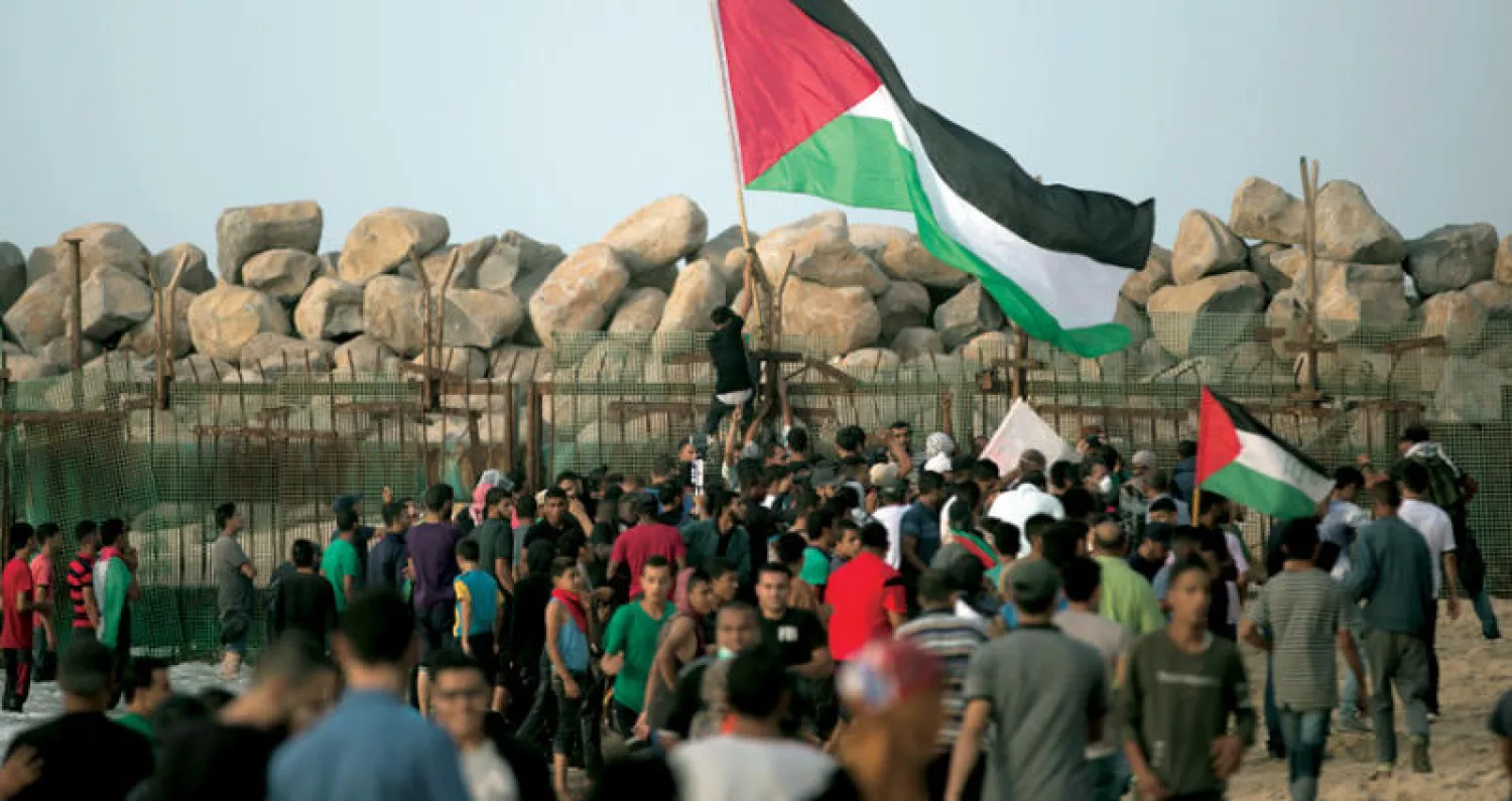 متظاهرون يرفعون العلم الفلسطيني عند الحاجز الحدودي شمال قطاع غزة (ا.ب)