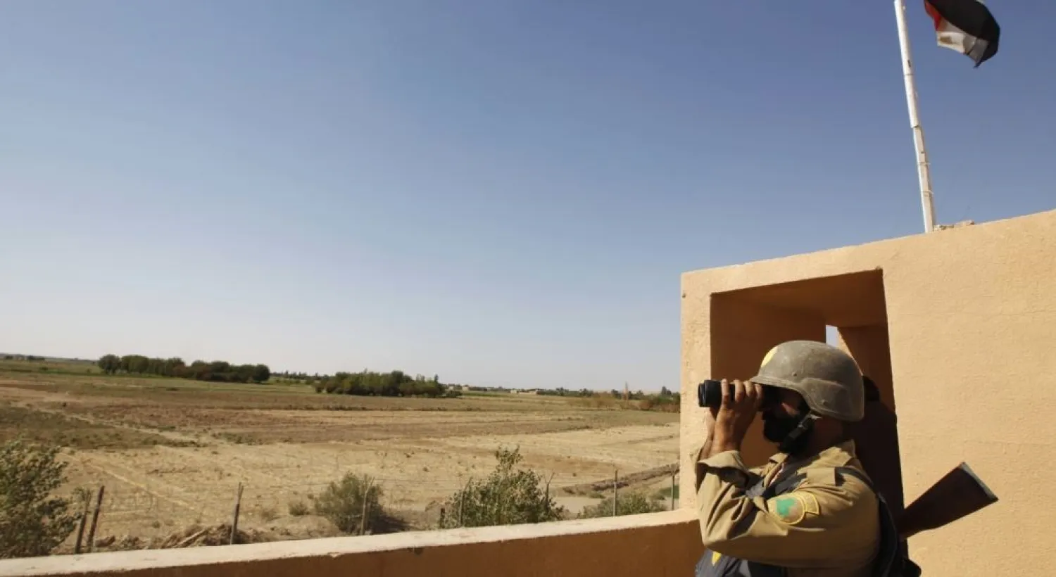 An Iraqi border policeman looks through a pair of binoculars near the Iraqi-Syrian borders. (Reuters)