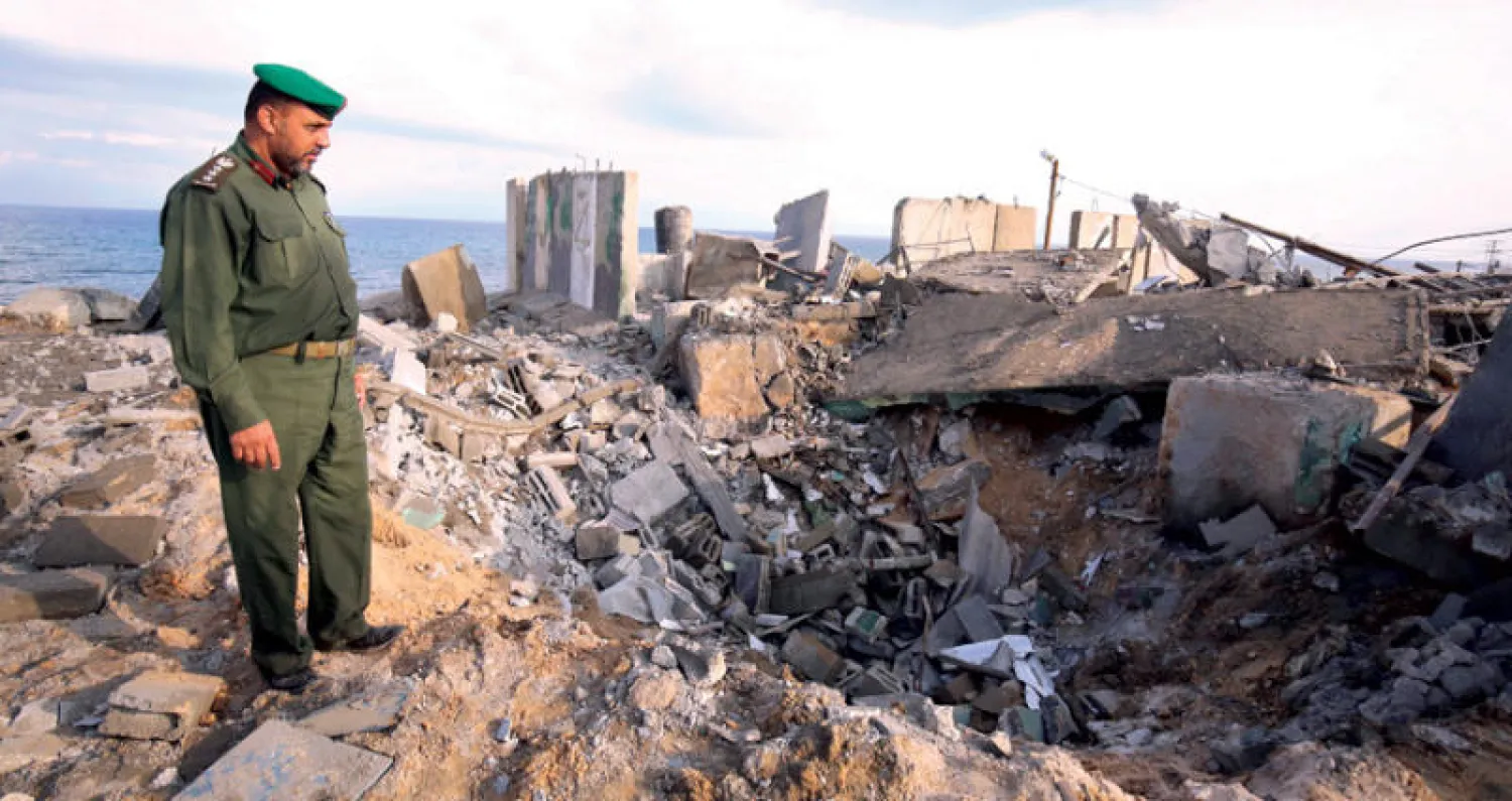 عنصر أمن فلسطيني يعاين الدمار الناجم عن غارة إسرائيلية على رفح في قطاع غزة أمس (أ.ف.ب)