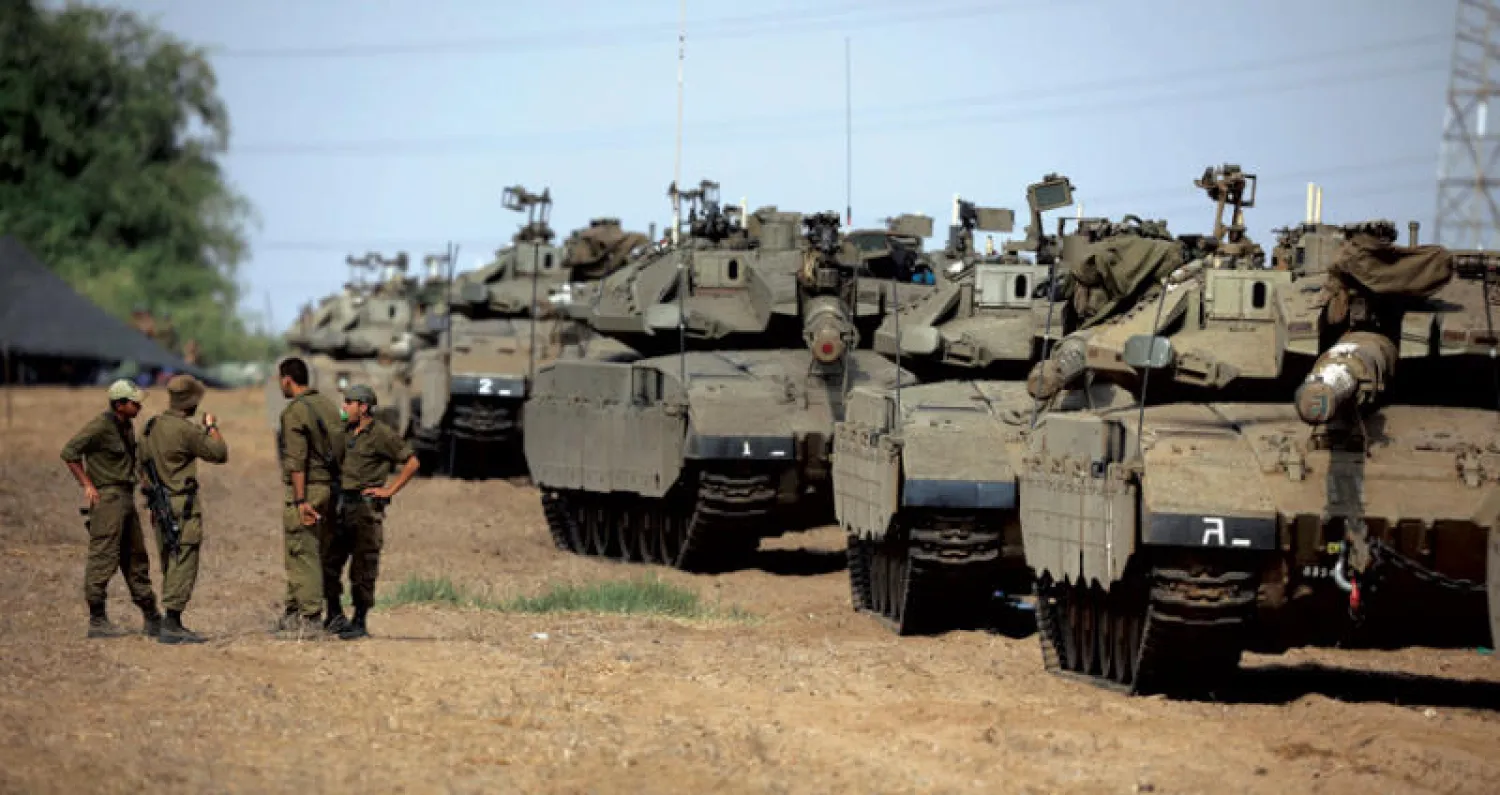 جنود إسرائيليون يتبادلون الحديث قرب رتل من الدبابات قرب الحدود مع غزة (رويترز)