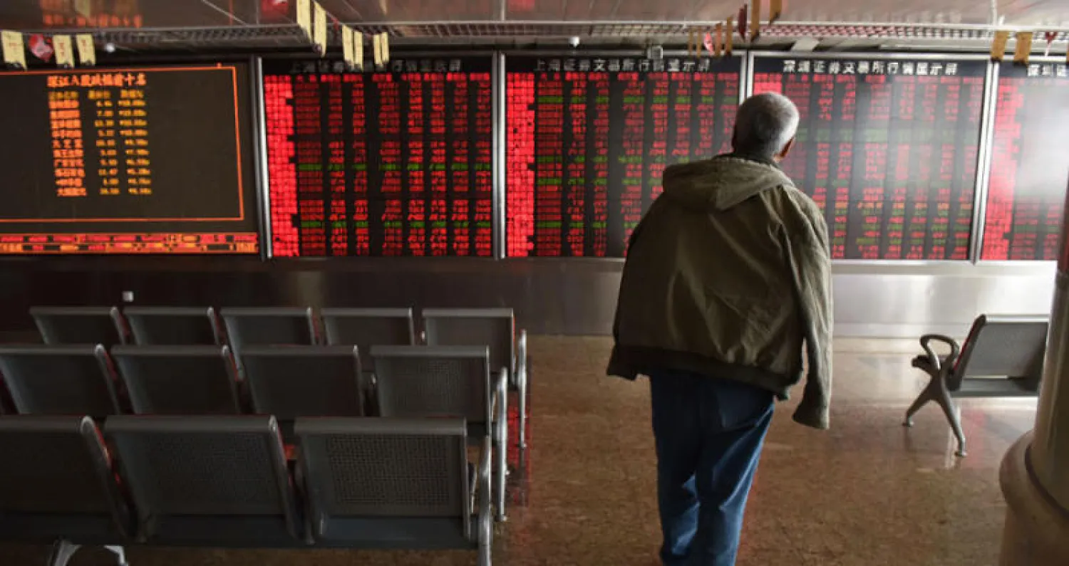 مستثمر يتابع أسعار الأسهم في شركة للأوراق المالية في بكين (أ.ف.ب)