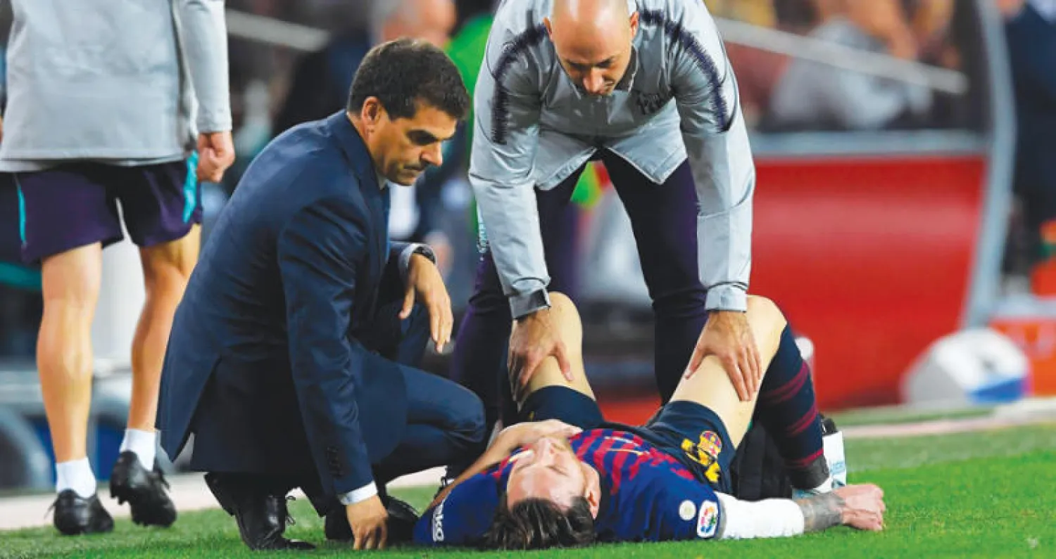 ميسي على الأرض يتلقى العلاج بعد إصابة ذراعه (أ.ف.ب)