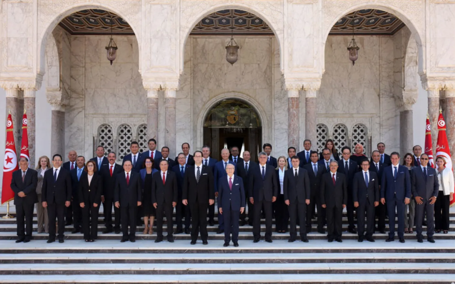 A handout picture provided by the Tunisian Presidency Press Service on August 27, 2016, shows Tunisian President Beji Caid Essebsi (C-R) posing for an official picture with his new Prime Minister Youssef Chahed (C-L) and members of his cabinet after the new government swearing-in ceremony at Carthage Palace, near the capital Tunis. | AFP