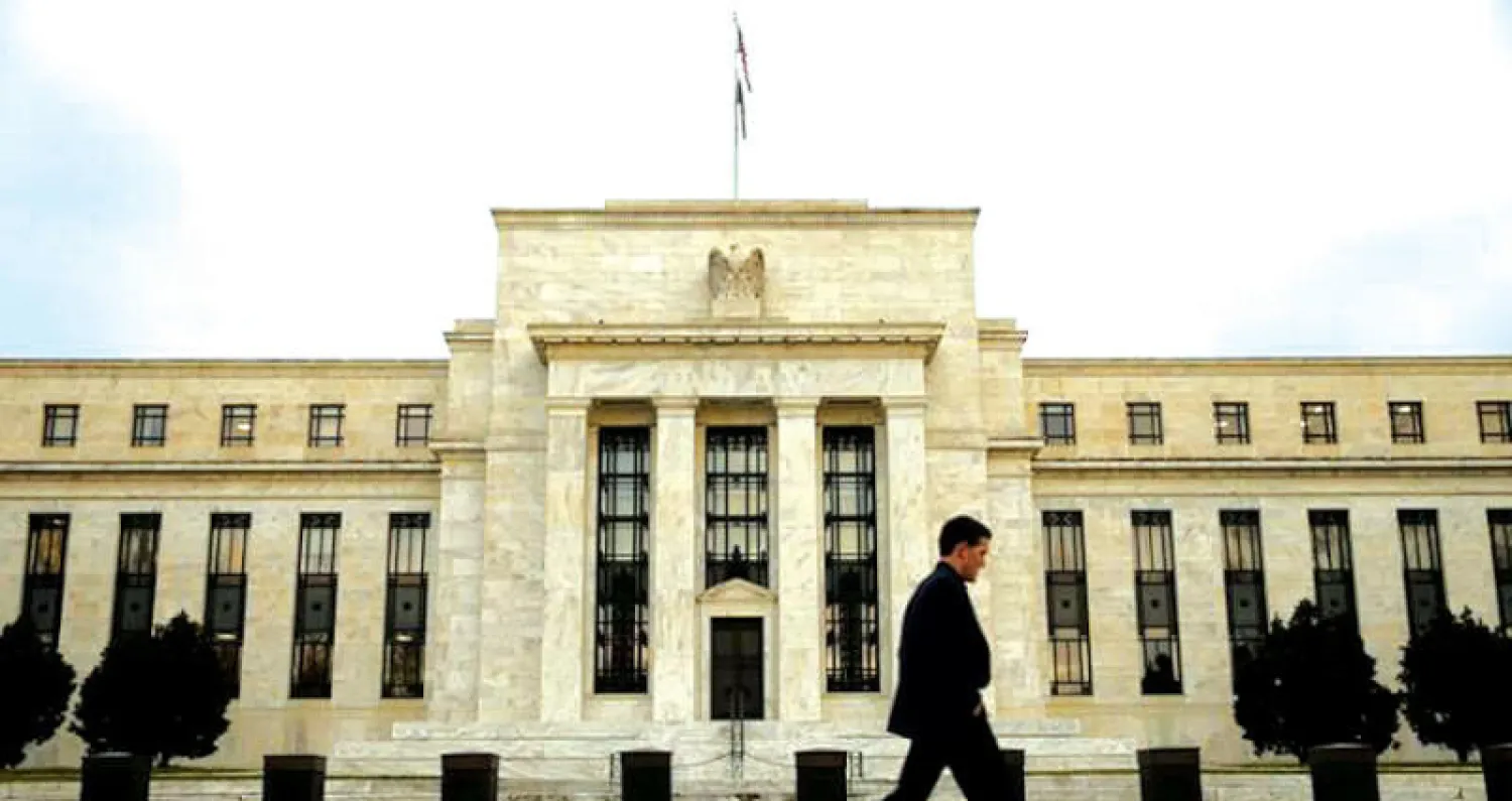 رجل يسير أمام البنك المركزي الأميركي في واشنطن (رويترز)