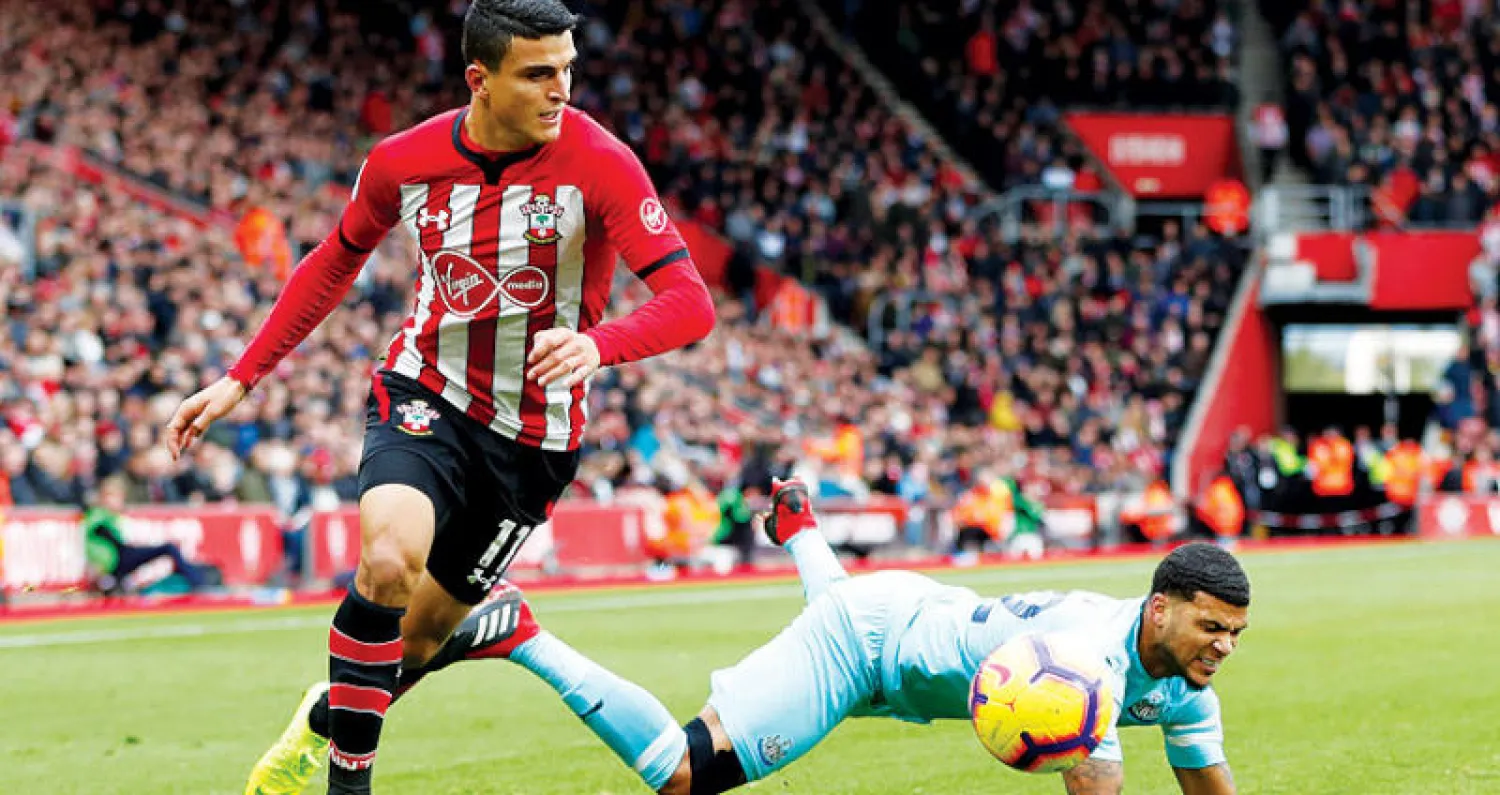 اليونسي مهاجم ساوثهامبتون ينطلق بالكرة متخطياً مدافع نيوكاسل (رويترز)