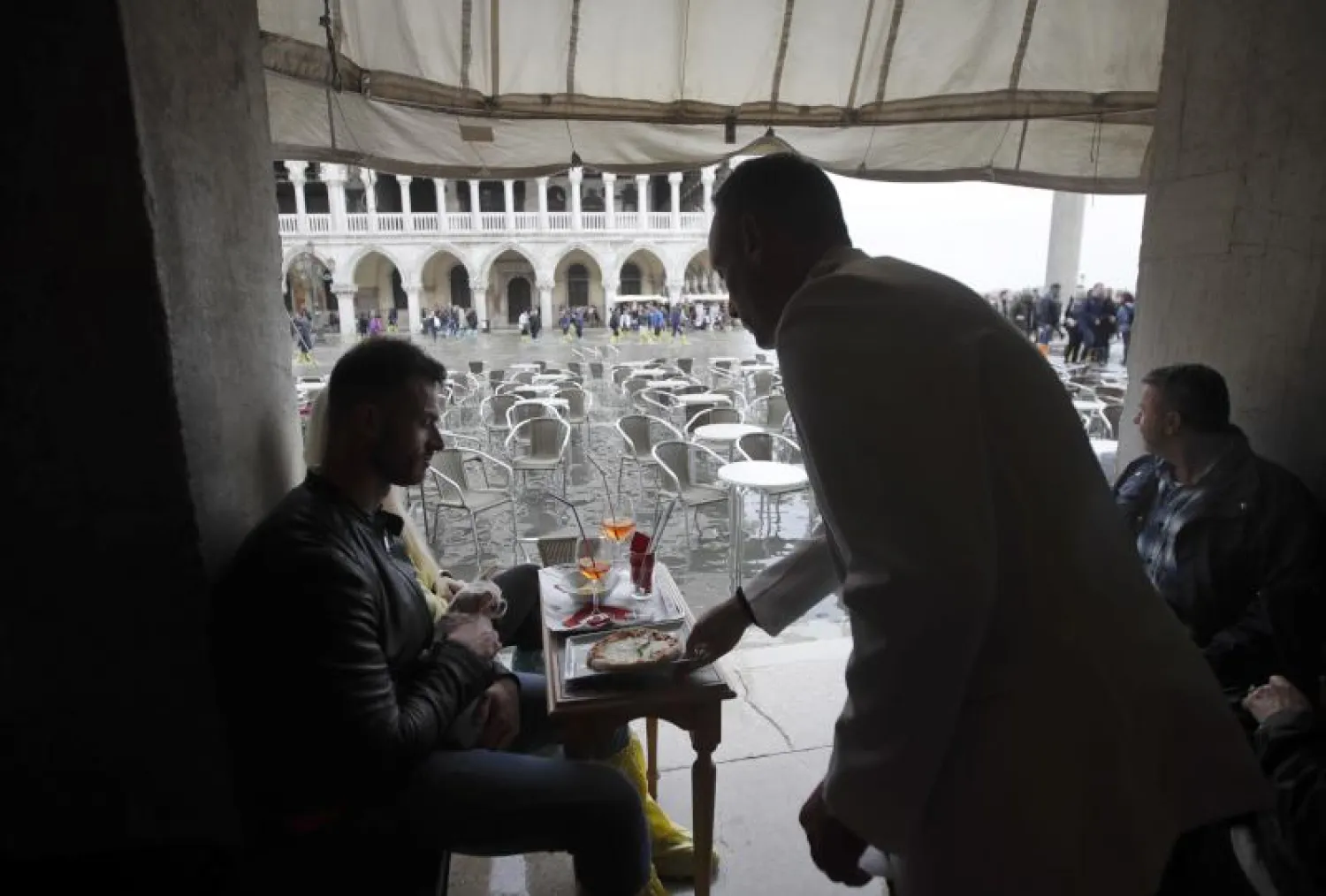 نادل يقدم البيتزا لأحد الزبائن في فينيسيا رغم الفيضانات التي اجتاحت المدينة (أ.ب)