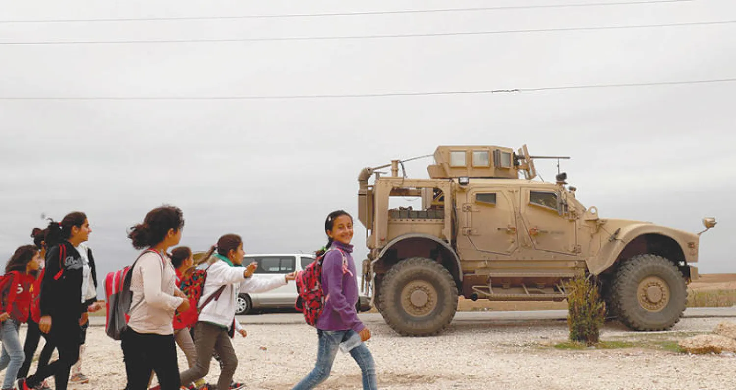 أطفال يمرون قرب عربة أميركية في الدرباسية شمال سوريا (أ.ف.ب)
