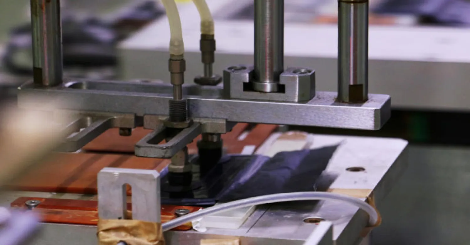 تقوم آلة الختم التلقائي بمعالجة بطارية أيونات الليثيوم المستخدمة في هواتف «آيفون» (رويترز)