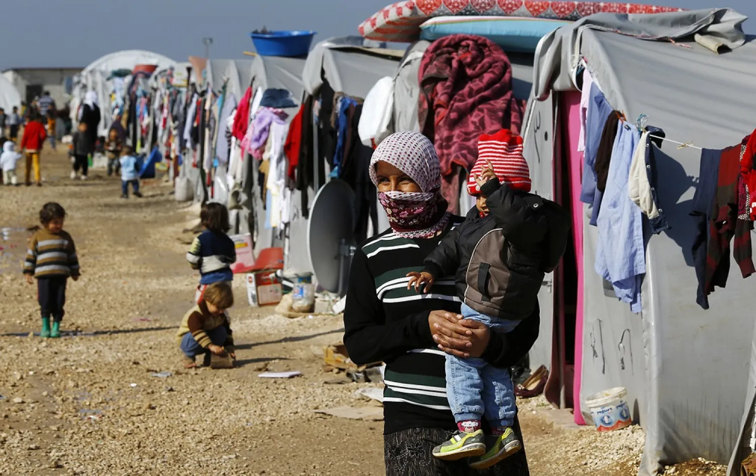 A refugee from the Syrian town of Kobani walks with her baby at a refugee camp in the border town of Suruc, Sanliurfa province. (Reuters)