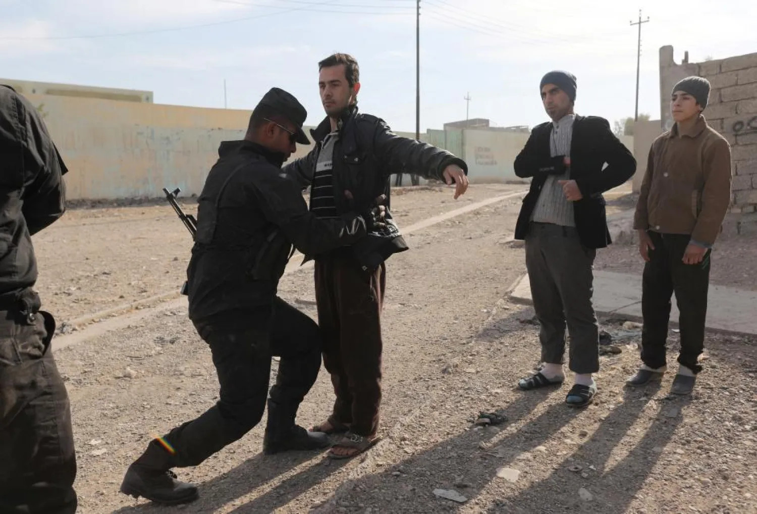 A member of an Iraqi special forces intelligence team searches men for weapons in Mosul, Iraq. (Reuters)