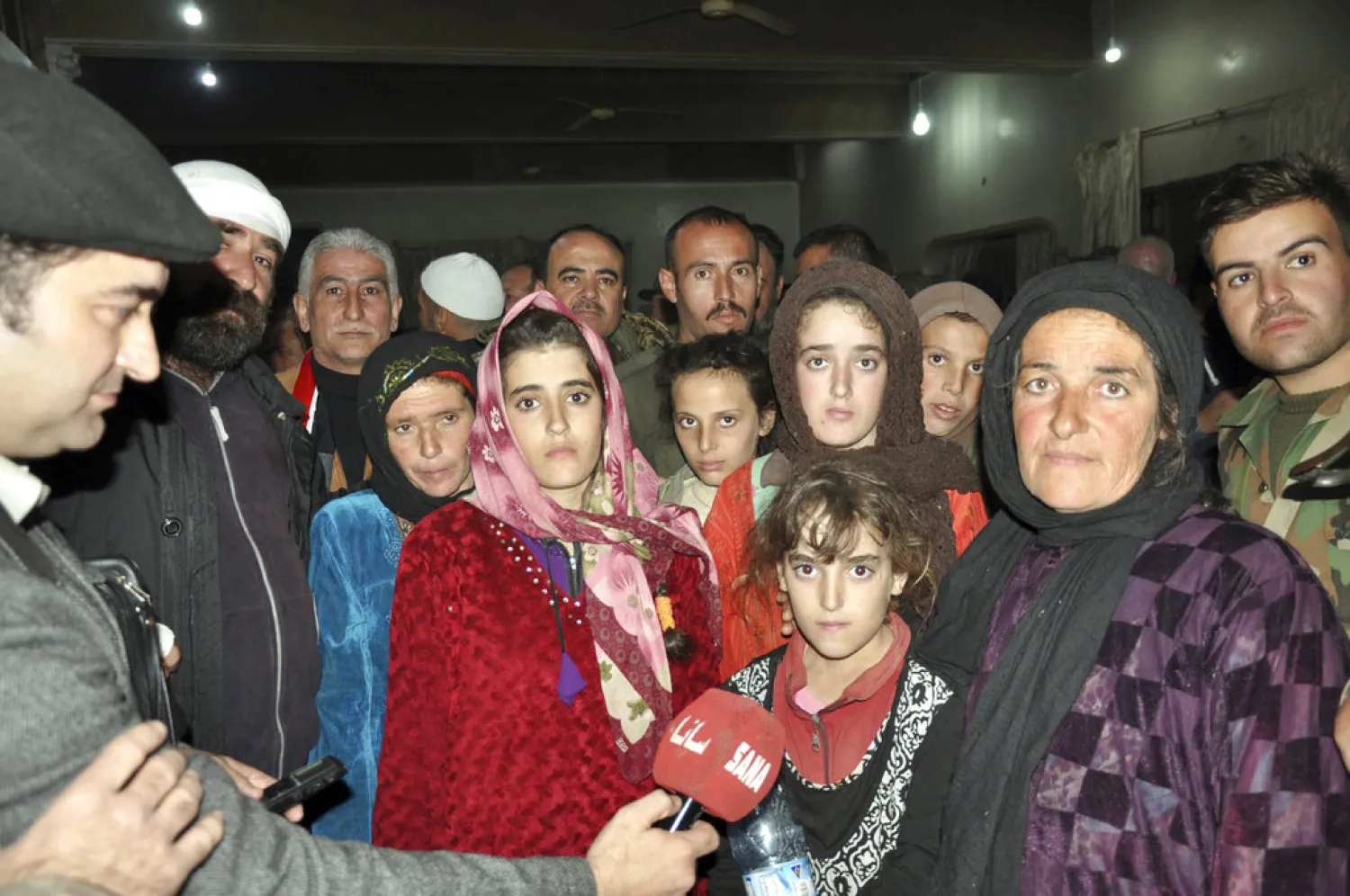 In this photo released by the Syrian official news agency SANA, women and children who were rescued from the Islamic State group in the Hamima area east of the historic town of Palmyra, after they arrived to the southern province of Sweida, Syria, Friday, Nov. 9, 2018. Islamic State group militants shot and killed two children during an operation to liberate a group of hostages from southern Syria that were being held by the extremist group since July, a father and activists said Friday. (SANA via AP)