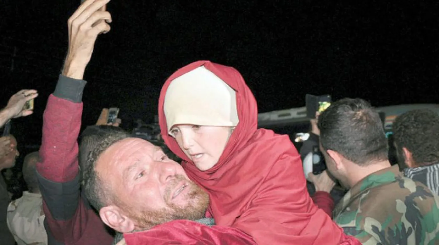 A man holds an young girl who has been rescued from ISIS in the Hamima area east of the historic town of Palmyra, after she arrived with others liberated hostages to the southern province of Sweida, Syria, Friday, Nov. 9, 2018. AP
