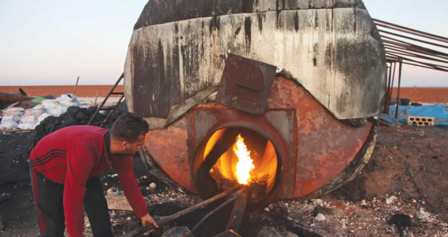 عامل في معمل بدائي للمحروقات في زردنة بريف إدلب لتصنيع الوقود المنزلي وغيره من مشتقات (إ.ف.ب)