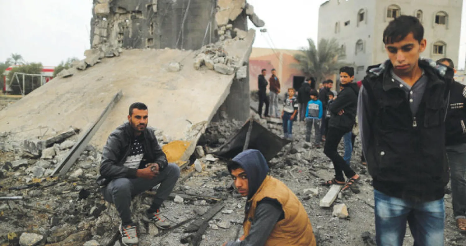 فلسطينيون يعاينون أنقاض مبنى في خان يونس بقطاع غزة دمرته غارة إسرائيلية أمس (رويترز)