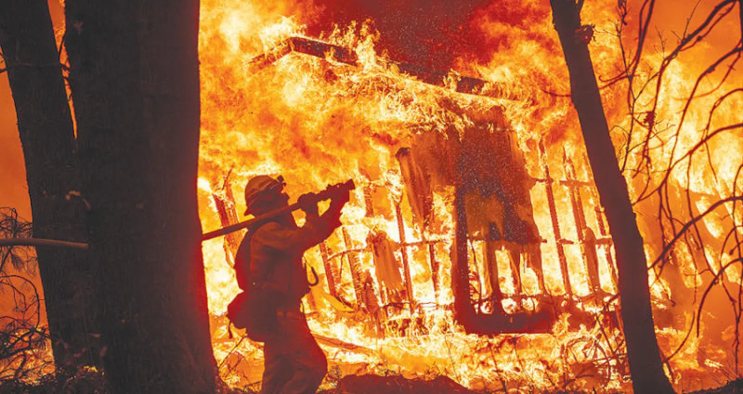 رجل إطفاء يحاول احتواء حريق التهم منزلاً في ماغاليا بولاية كاليفورنيا (أ.ب)