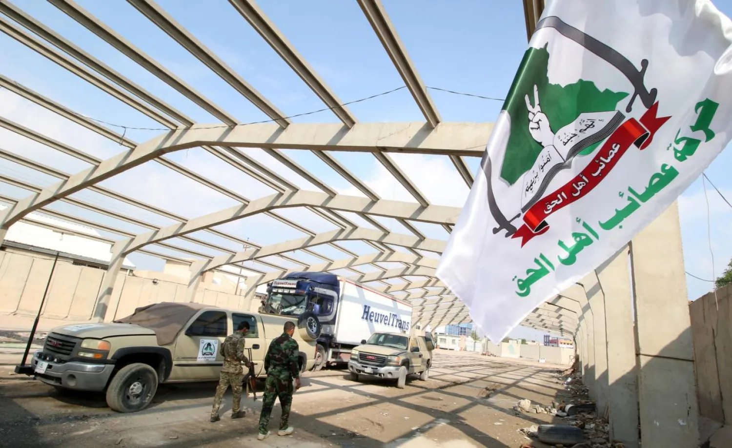 Members of Shi'ite group Asaib ahl al-Haq walk outside their premises in Basra, Iraq November 8, 2018. The text on the flag reads: 'Asaib ahl al-Haq Movement'. Picture taken November 8, 2018. REUTERS/Essam al-Sudani
