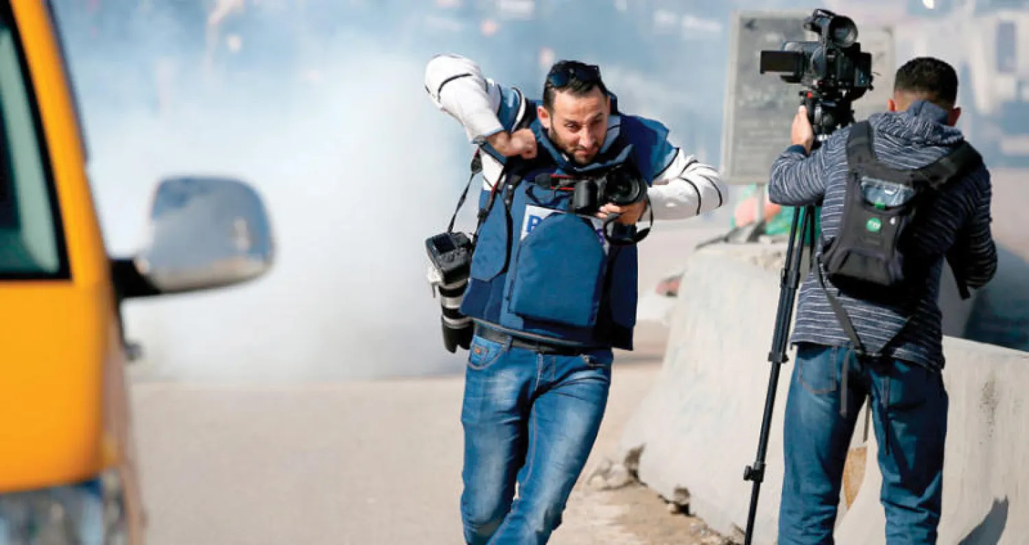 صحافي يفر من قنابل الدخان في رام الله (أ.ف.ب)