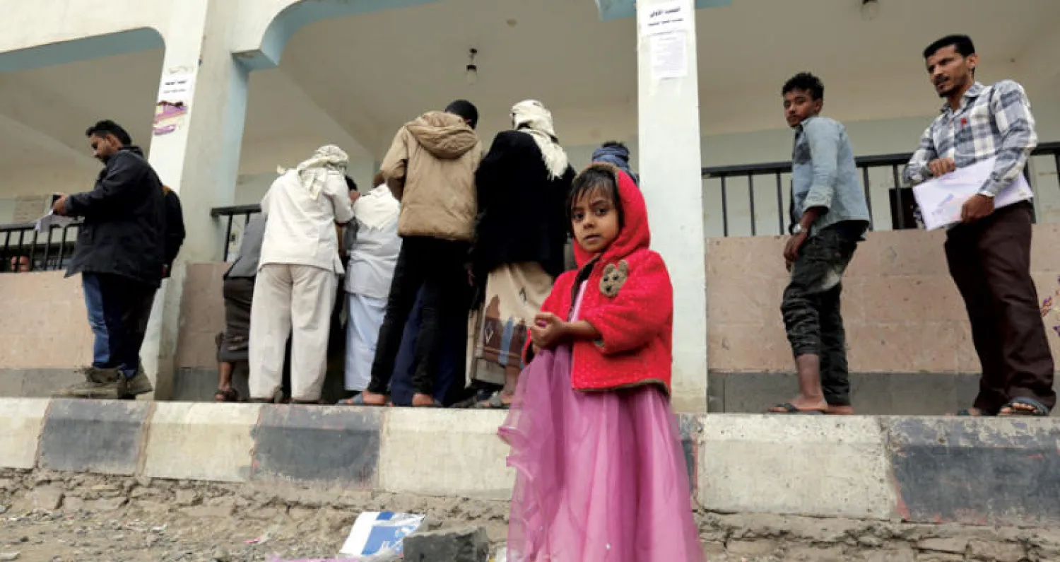 طفلة تنتظر والدها الذي يسجل وآخرون بياناتهم في سجلات النازحين بصنعاء (إ.ب.أ)