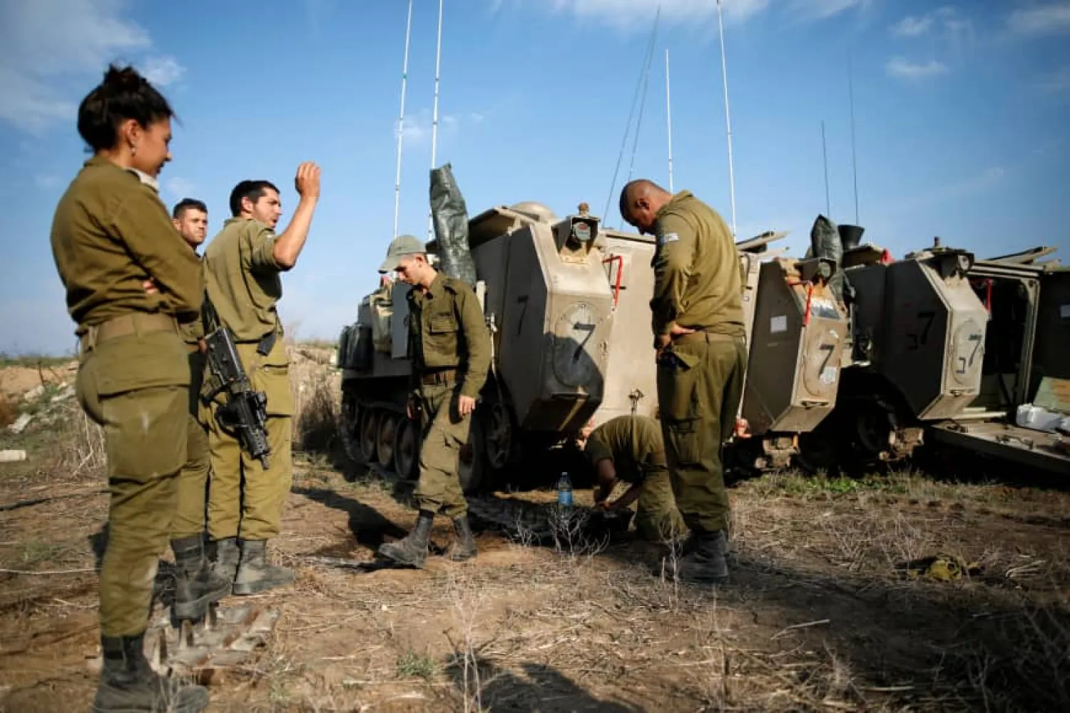 Israeli soldiers stand next to armored personnel carriers in a field in southern Israel, near the border with Gaza. (Reuters)