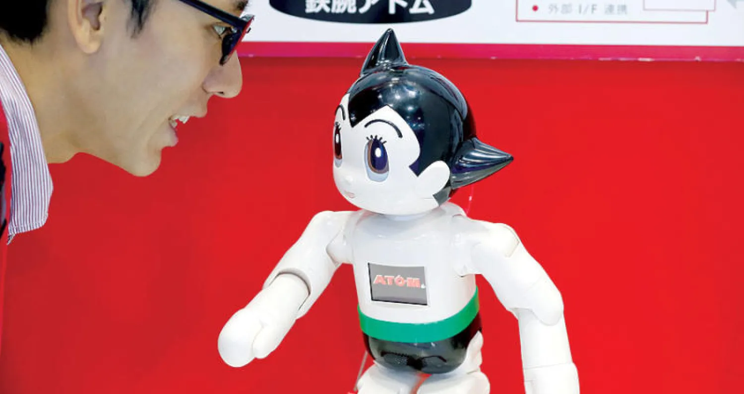 أحد الموظفين يتحدث إلى روبوت خلال مشاركته  في قمة الروبوت العالمية في طوكيو (رويترز)