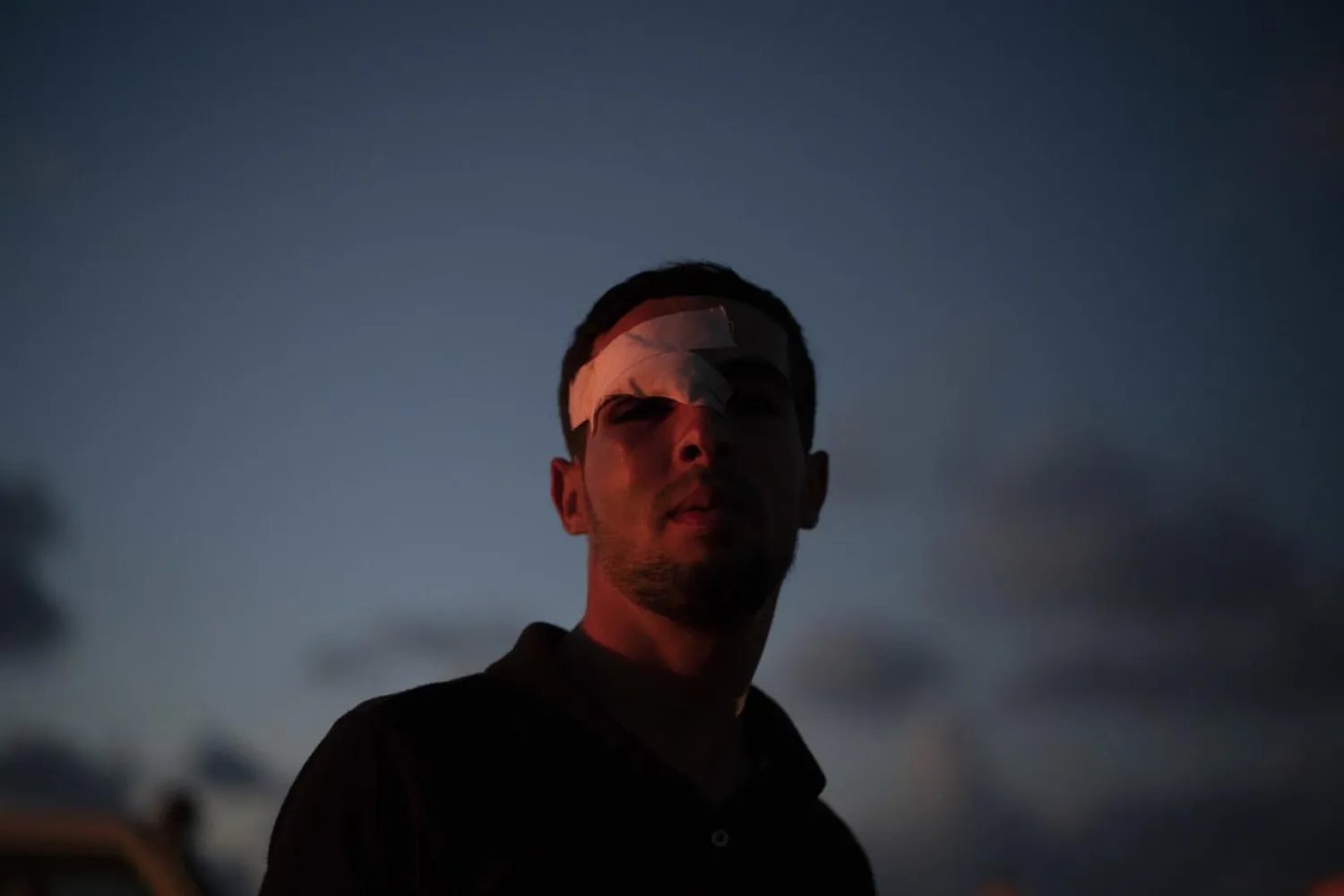 In this Friday, Sept. 14, 2018 photo, a Palestinian who was injured during a protest stands after sunset near the Gaza Strip's border with Israel, east of Gaza City. (AP Photo/Felipe Dana)