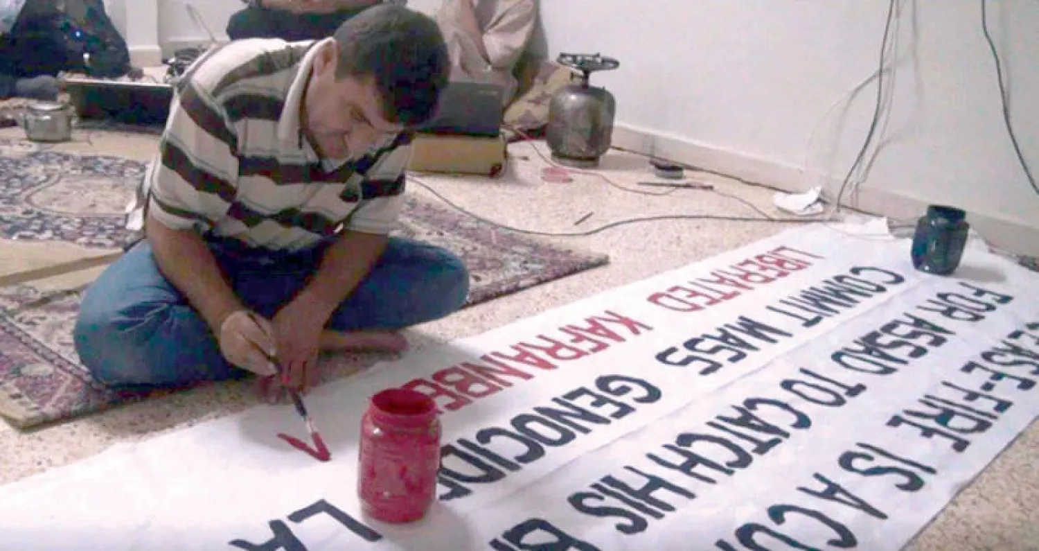 صورة أرشيفية لرائد فارس وهو يكتب لافتة (أخبار كفرنبل)