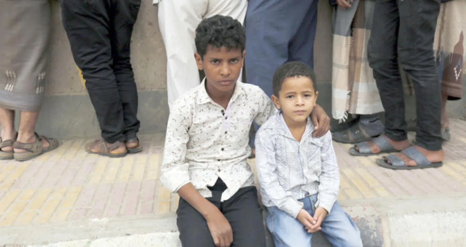 طفلان يجلسان قرب مركز لتسجيل النازحين في صنعاء (إ.ب.أ)