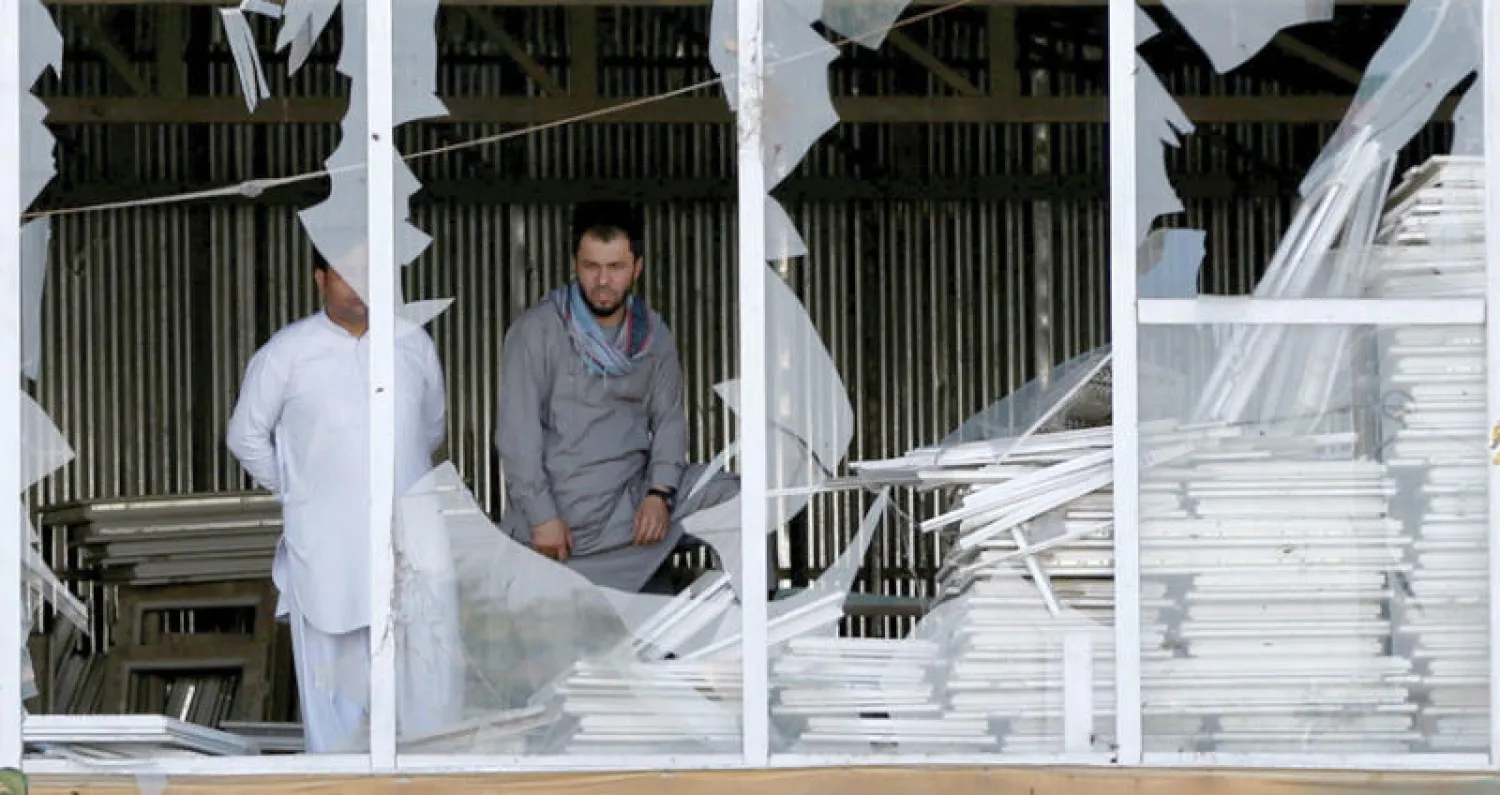 أفغانيان داخل متجر تهشمت واجهته الزجاجية بفعل تفجير انتحاري في كابل (رويترز)