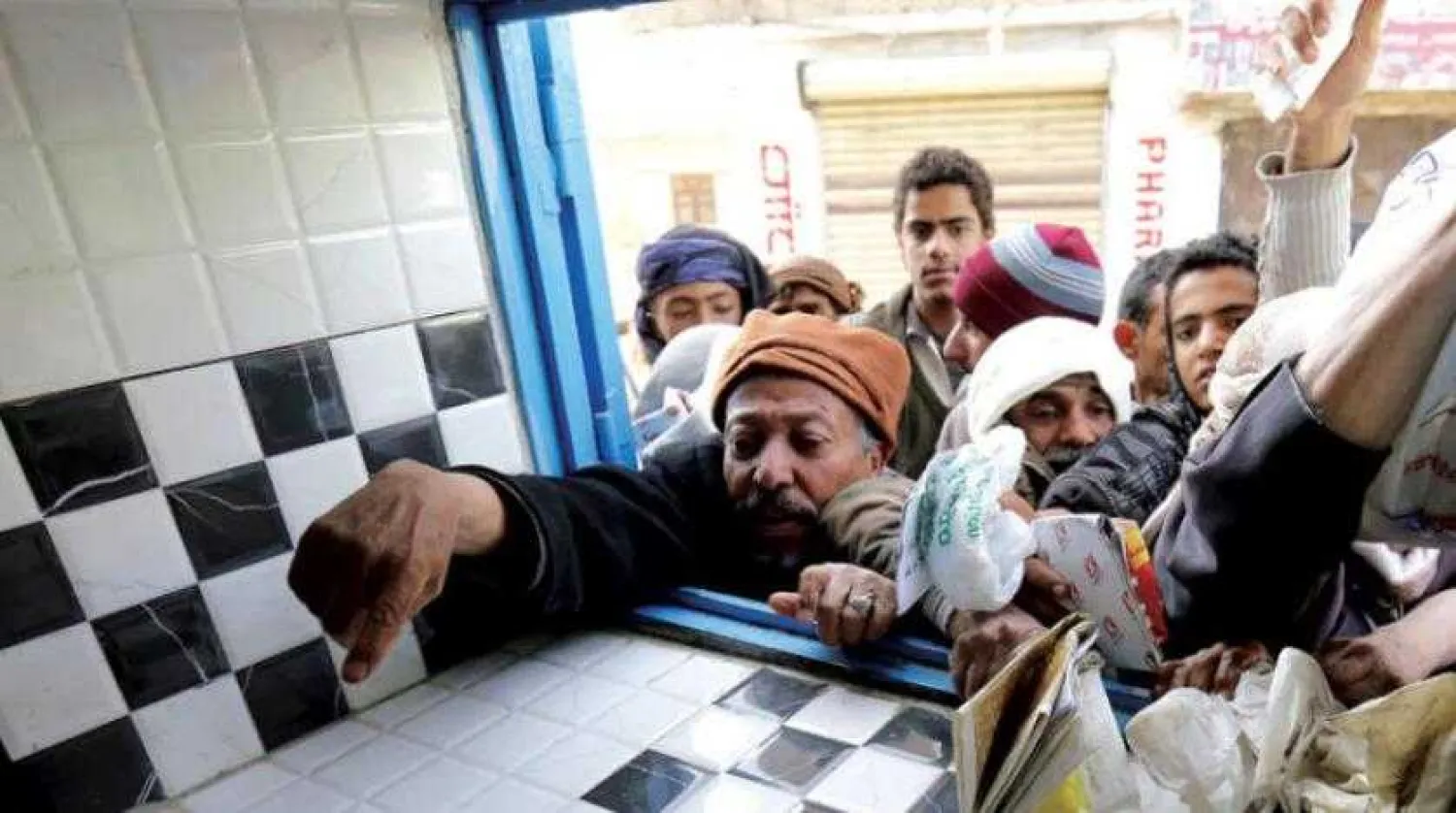 Crowds gather in front of a charity shop distributing bread in Sanaa (EPA)