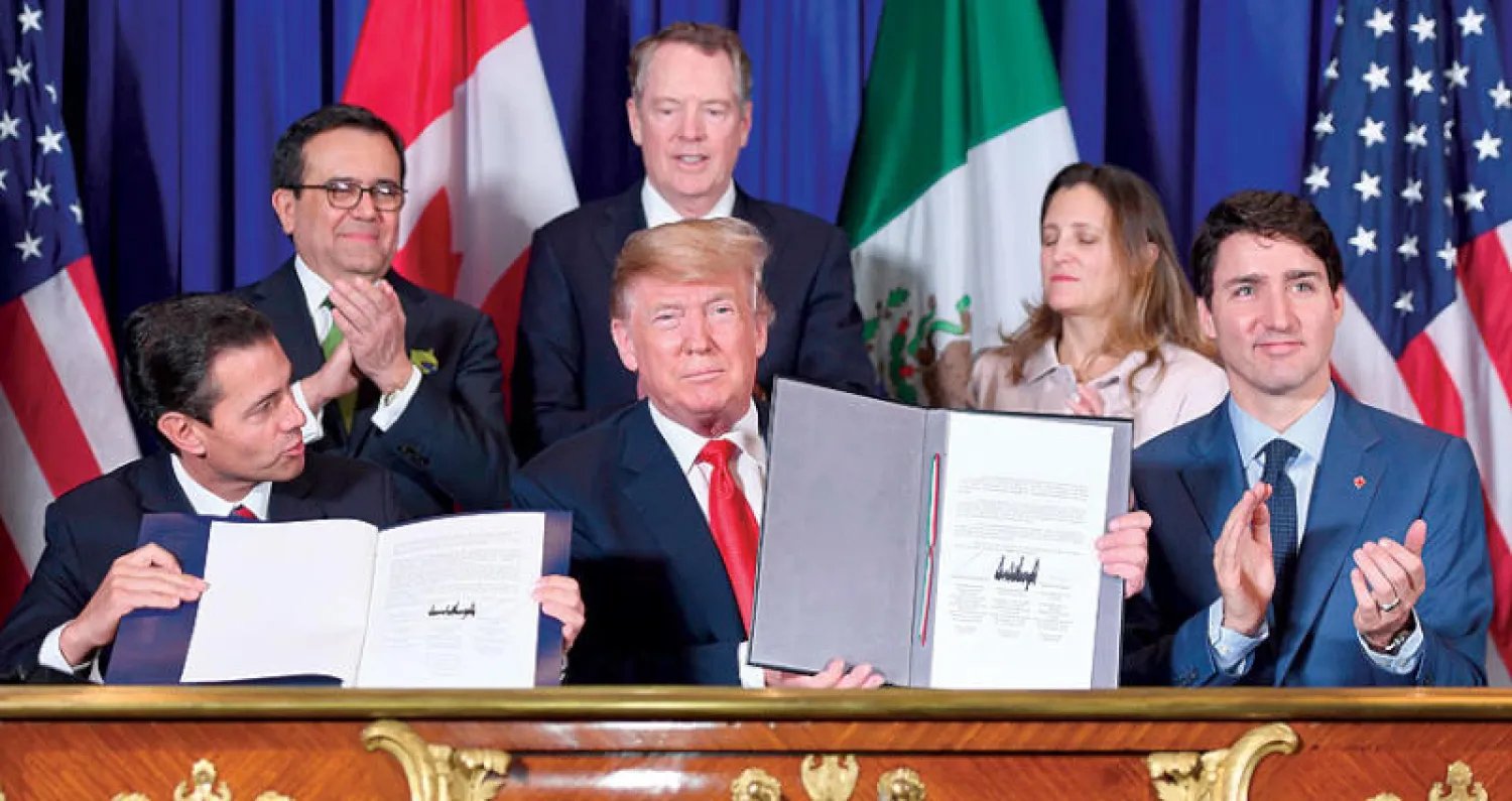 الرئيس ترمب يتوسط رئيس الوزراء الكندي جاستن ترودو والرئيس المكسيكي إنريكي بيان نيتو عقب توقيعهم الاتفاقية الجديدة أمس (أ.ف.ب)