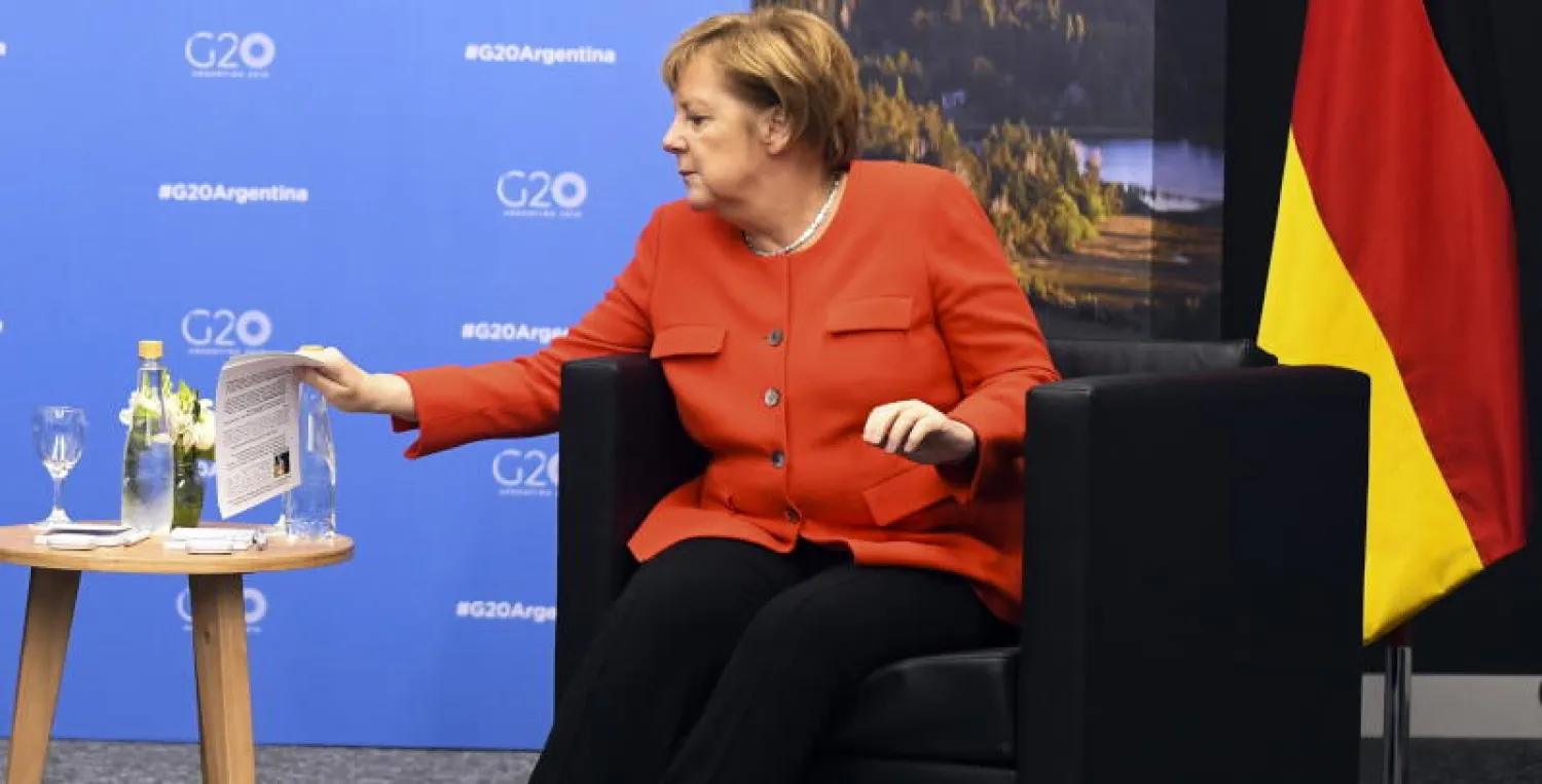 المستشارة الألمانية أنجيلا ميركل تضع ورقة معلومات عن نظيرها الأسترالي سكوت موريسون (إ.ب.أ)