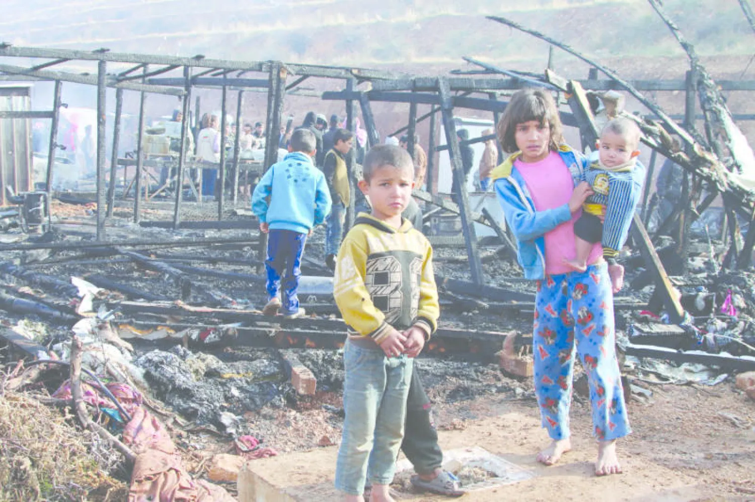 نازحون سوريون يعاينون الدمار الذي لحق بخيمهم بعد حريق في مخيم ببلدة اليمونة شرق لبنان (أ.ف.ب)