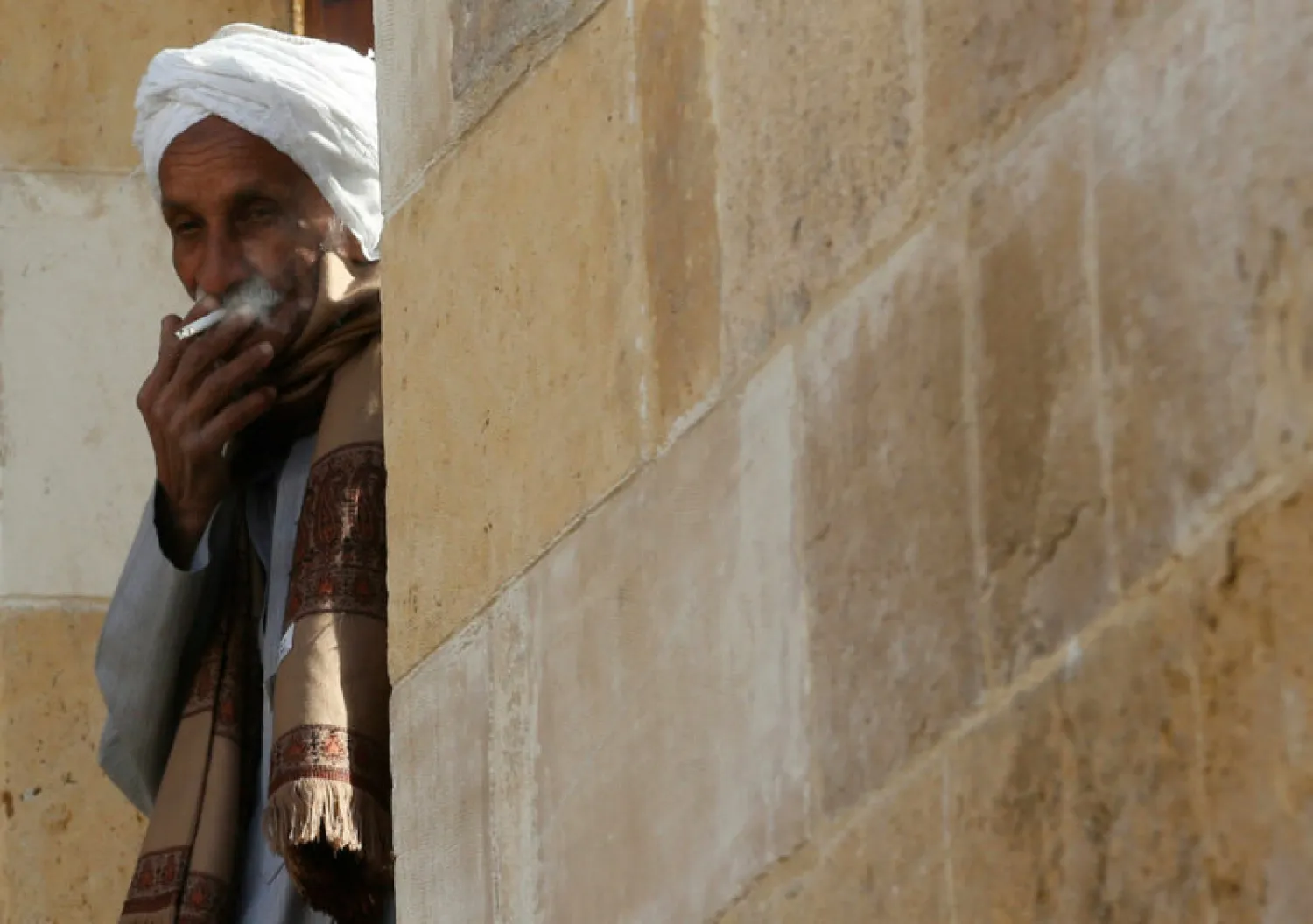 An elderly man smokes his cigarette in front of his house at Manshiet Nasser shanty town in the capital Cairo. (Reuters)
