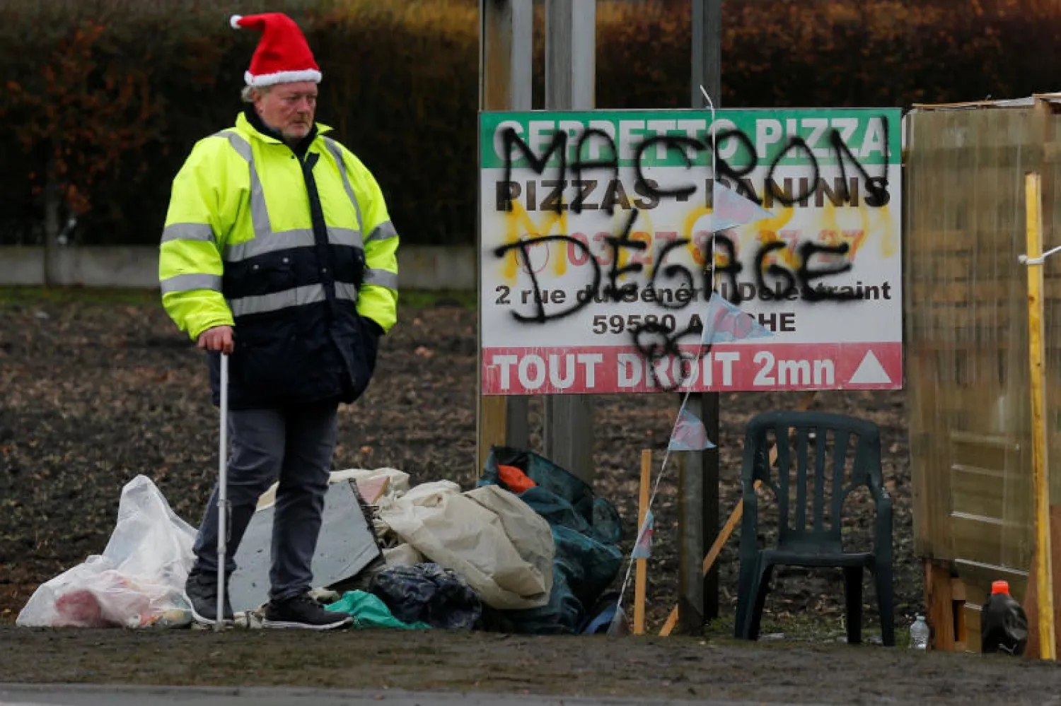 محتجّ في سومان بشمال فرنسا قرب لافتة كُتب عليها: ماكرون إرحل (رويترز)