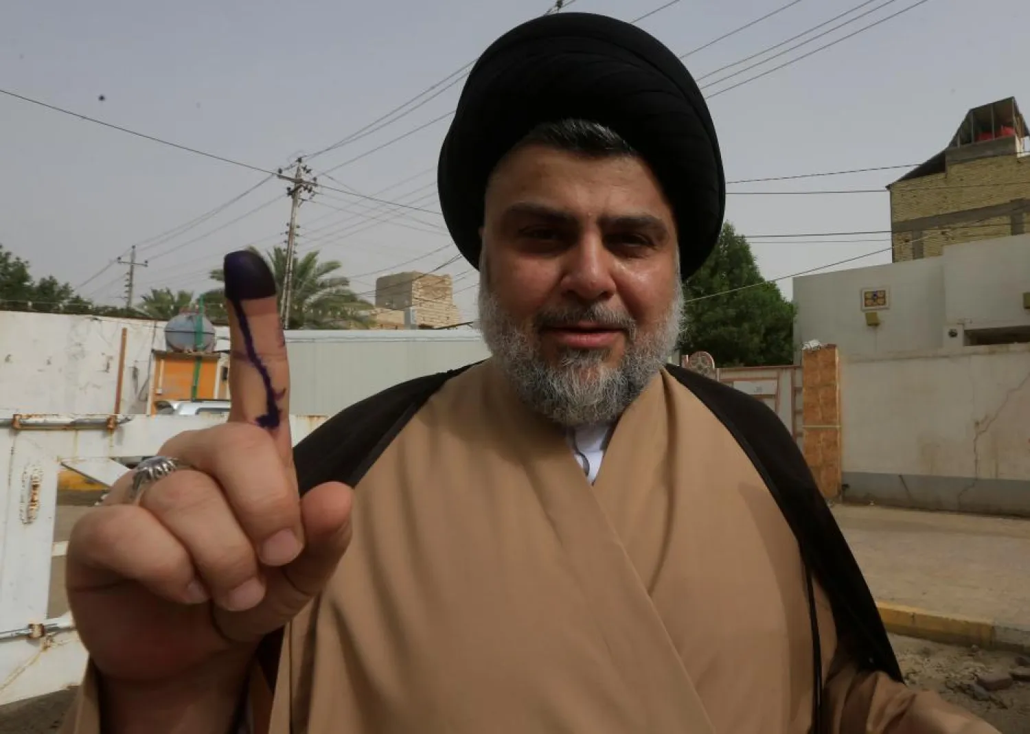 Head of the Sadrist movement Moqtada al-Sadr shows his ink-stained finger after casting his vote at a polling station during the parliamentary election in Najaf, Iraq May 12, 2018. REUTERS/Alaa al-Marjani