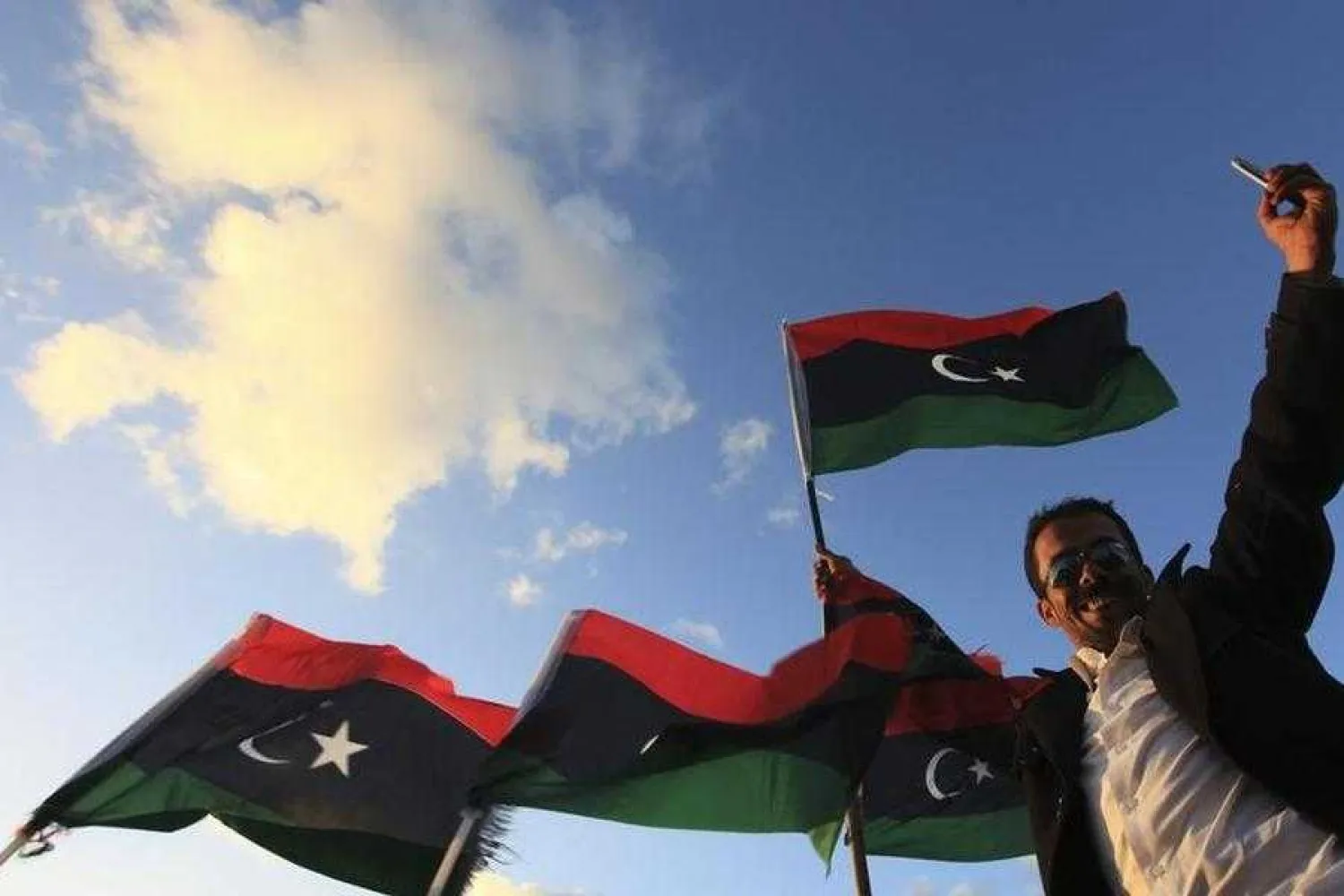 A man smiles next to Libyan flags in Benghazi February 17, 2013. REUTERS/Esam Al-Fetori