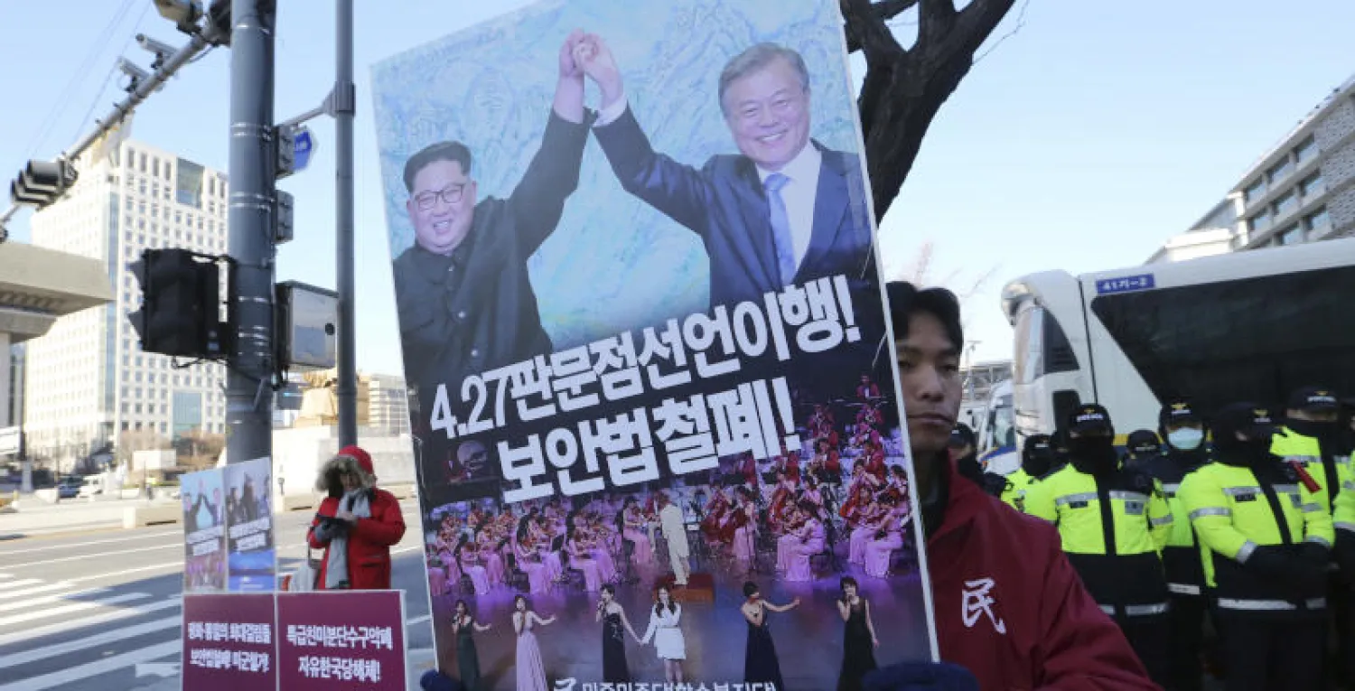 مواطن كوري جنوبي يحمل لافتة تظهر صورة للزعيم الكوري الشمالي كيم جونغ أون والرئيس الكوري الجنوبي مون جاي (أ.ب)