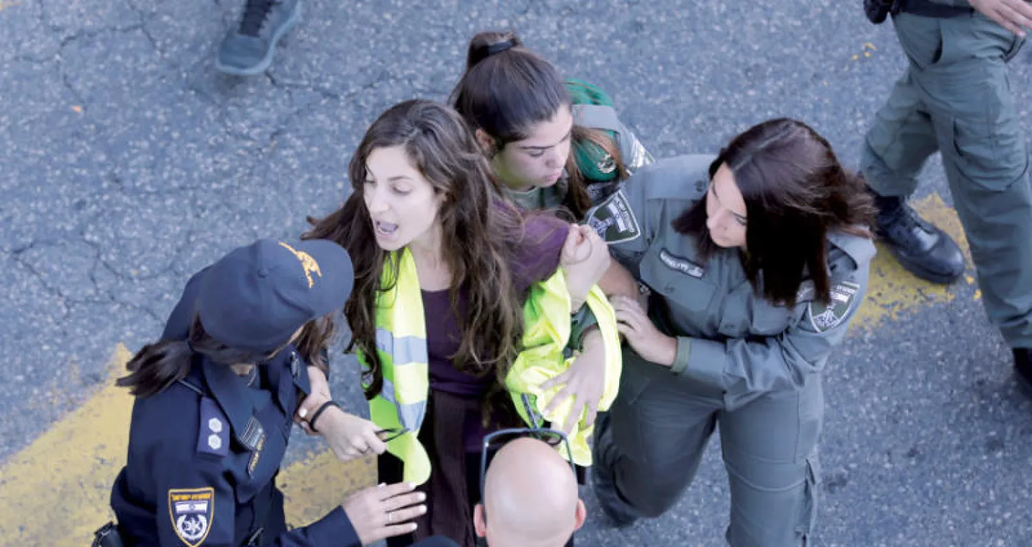 شرطيات اسرائيليات يعتقلين متظاهرة من ذوي {السترات الصفراء} في تل أبيب أمس (إ.ب.أ)