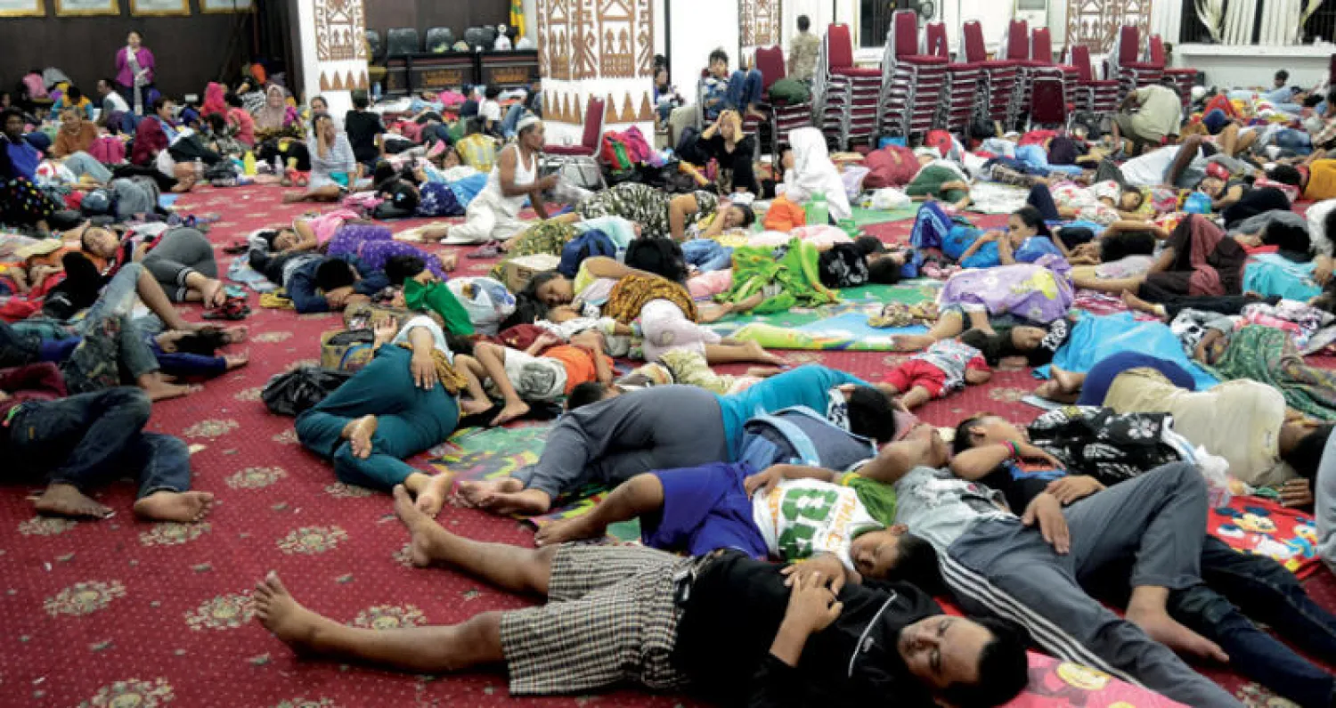 عدد من مشردي «تسونامي» في انتظار المساعدات داخل أحد المجمعات الحكومية في بلدة باندر لامبونغ (رويترز)