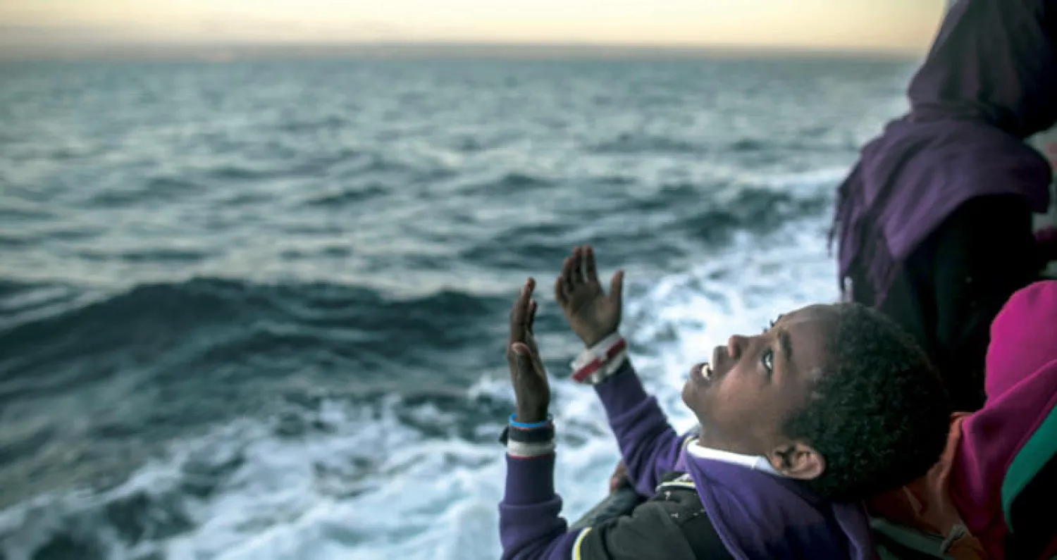 طفل من إريتريا يرفع يديه شكراً لله بعد أن تمكّن من الوصول إلى أوروبا إثر إنقاذه من طرف خفر السواحل الإسباني (أ.ب)