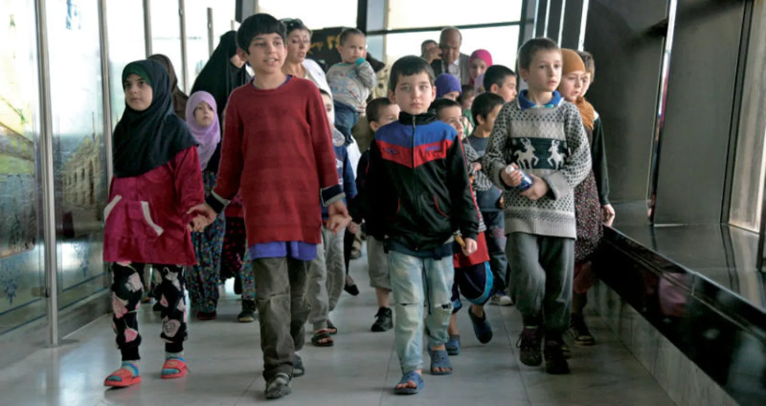 مجموعة من الأطفال العائدين في طريقهم إلى طائرة في مطار بغداد تقلهم إلى موسكو (إ.ب.أ)