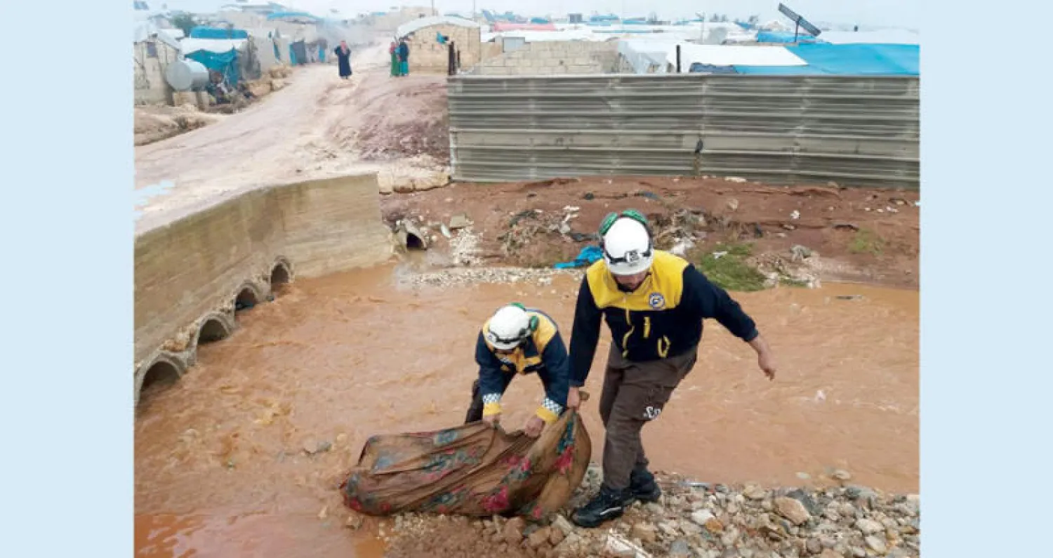 عناصر الدفاع المدني يزيلون مياهاً من مخيمات للنازحين في ريف إدلب أمس (الدفاع المدني)