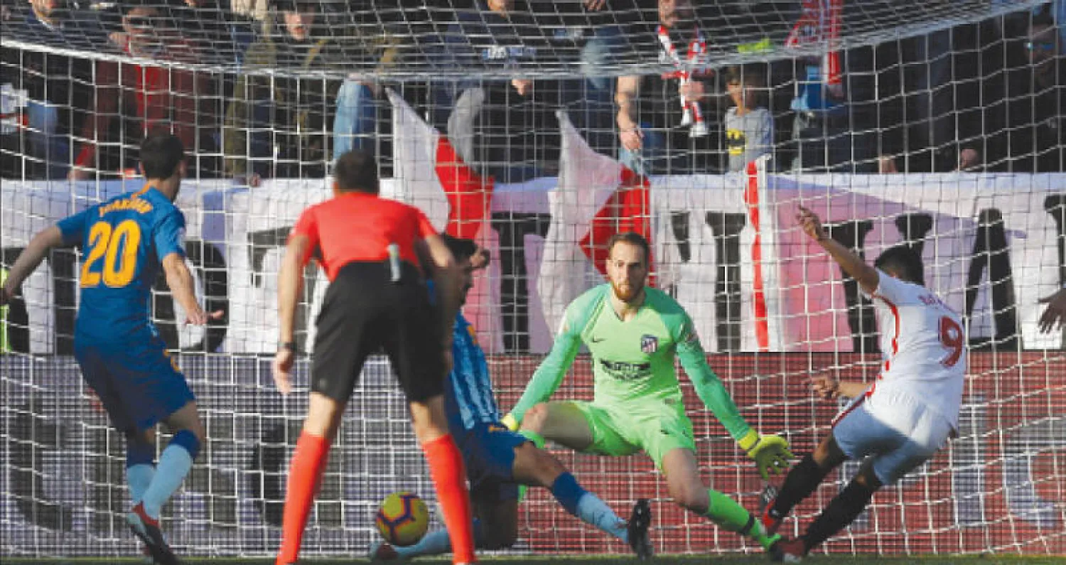 بن يدر (يمين) يسجل هدف إشبيلية في مرمى اتلتيكو بقمة المرحلة (رويترز)