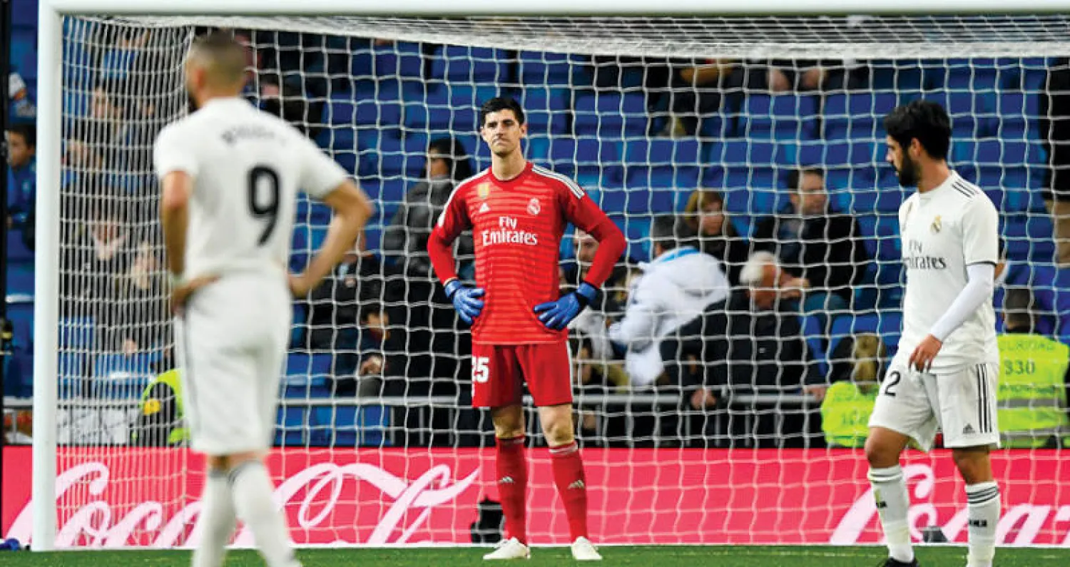 كورتوا حارس ريال مدريد ينظر لمدافعيه في حسرة بعد أن اهتزت شباكه بهدفين أمام سوسييداد (أ.ف.ب)