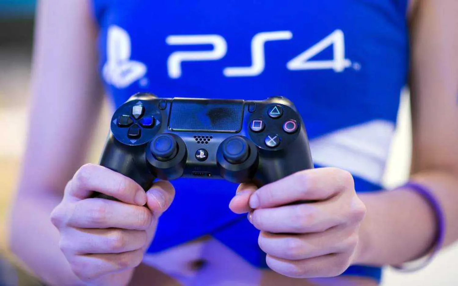 A hostess holds a remote of a Playstation 4 at the Sony booth during the China Joy fair in Shanghai. (JOHANNES EISELE/AFP)