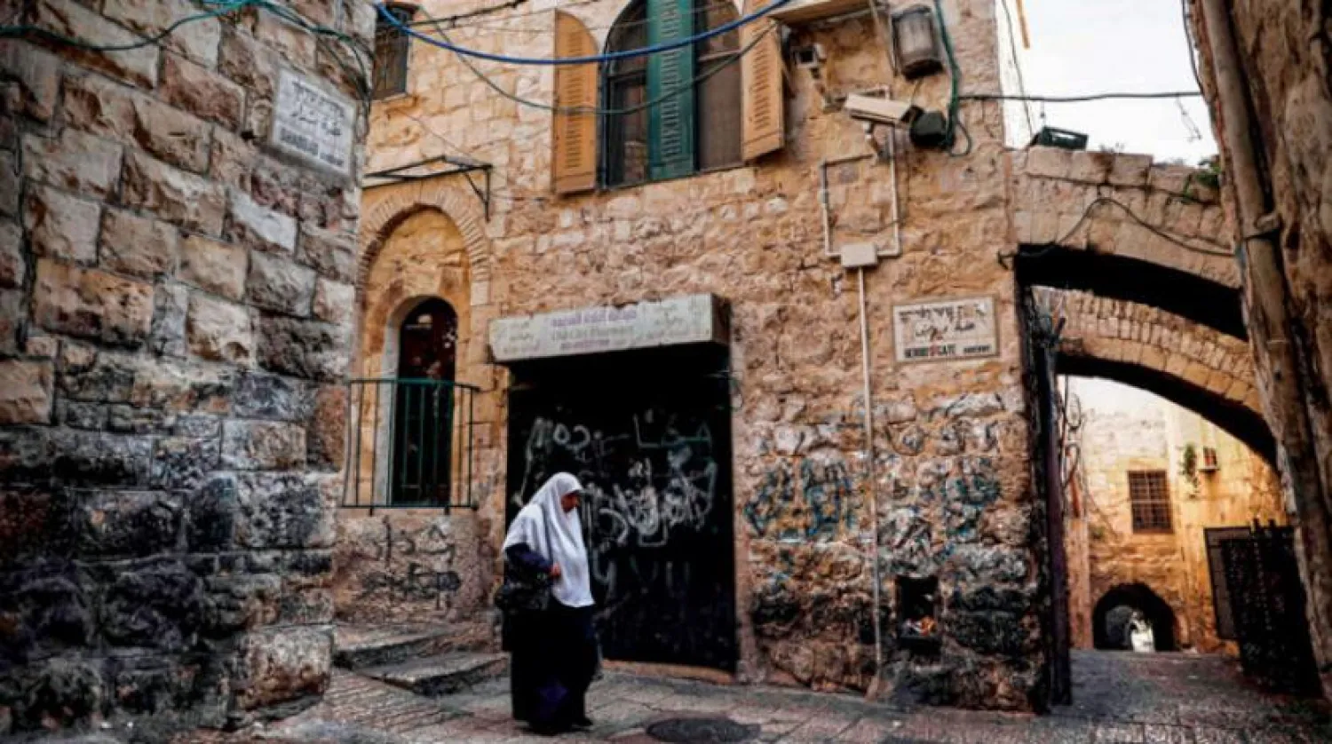 A Palestinian woman passing by Beit Jouda in the Old City of Jerusalem thst was bought by settlers through a suspicious deal in which the Palestinian Authority has been investigating. (AFP)