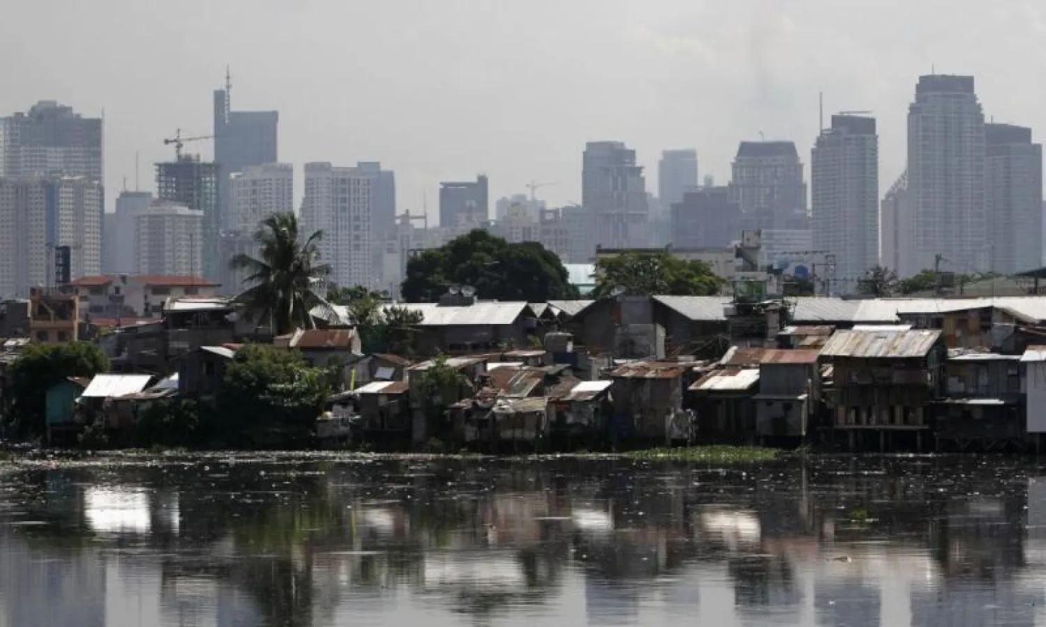مبانٍ شاهقة في الخلفية وأمامها مساكن فقيرة في مانيلا - أرشيف (رويترز)