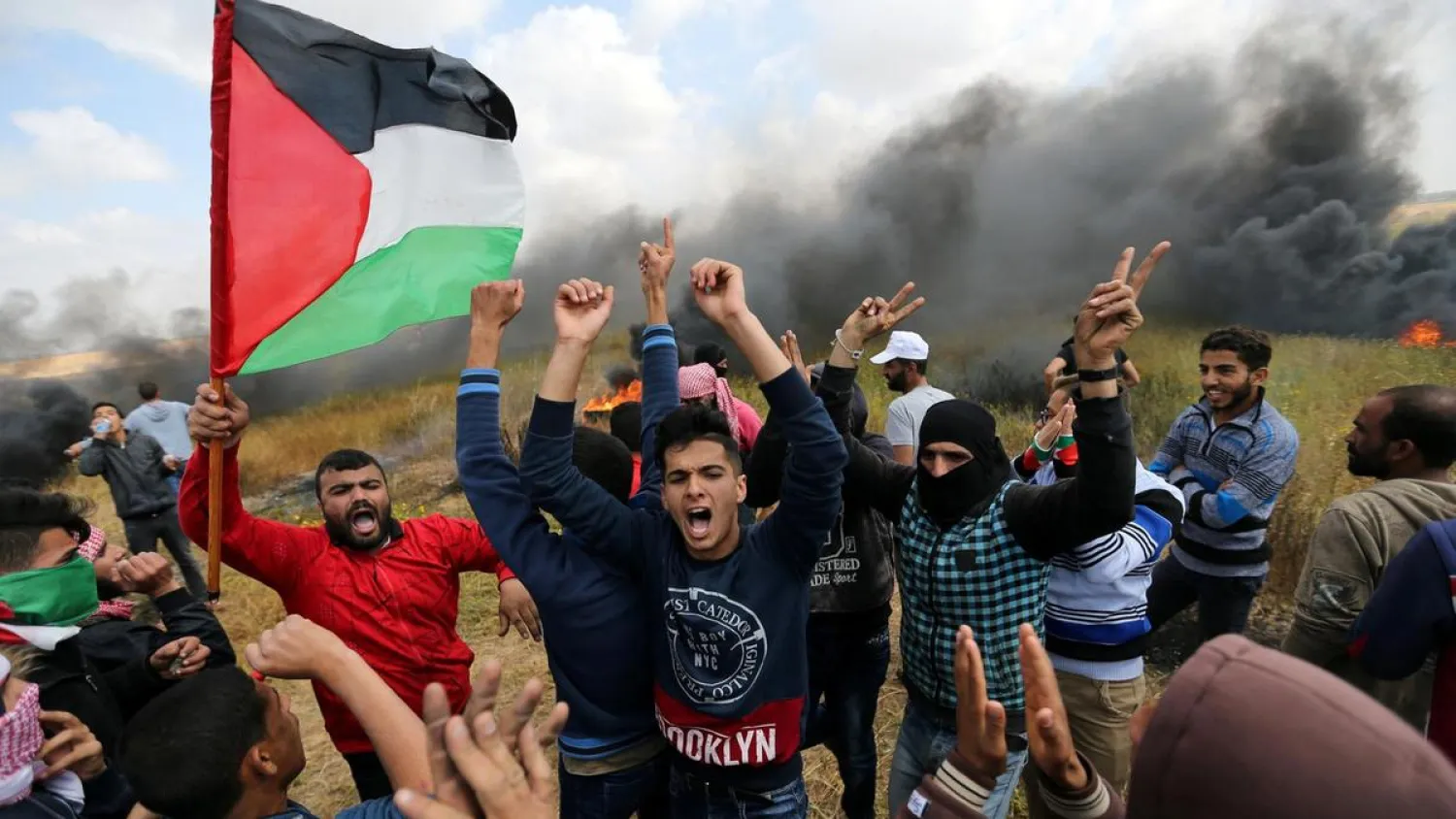 Smoke billows behind a group of Palestinians during a protest along the Israel border with Gaza. (Reuters)