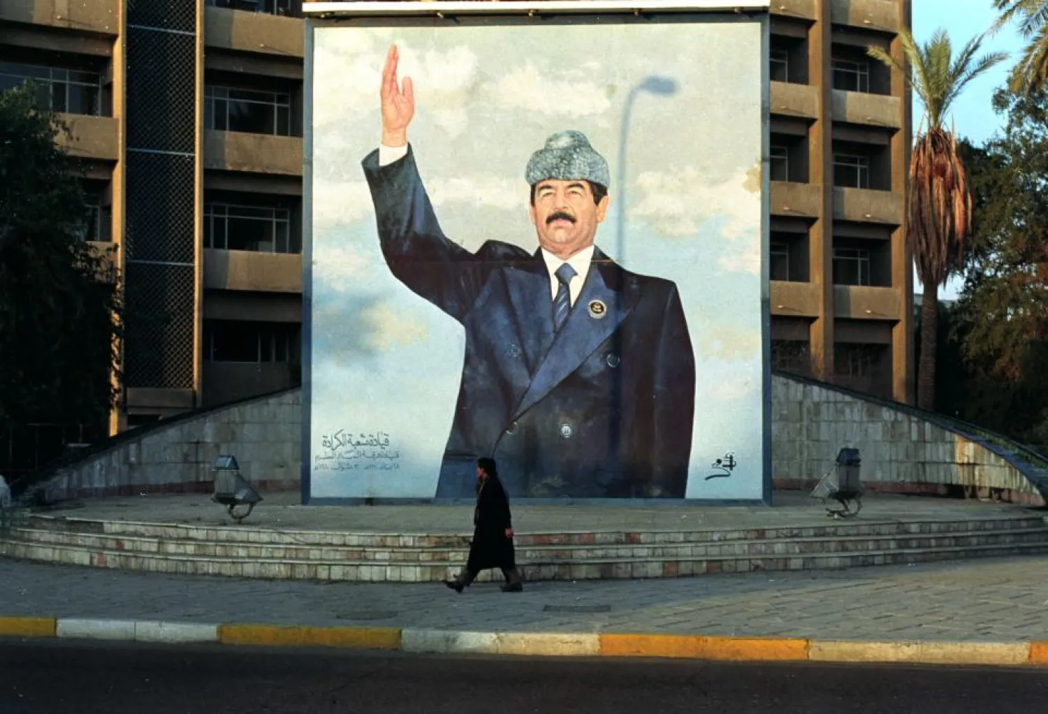 An Iraqi resident walks past a poster of Saddam Hussein. (Reuters)